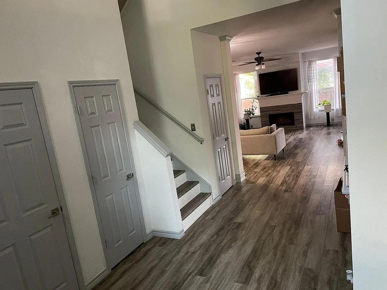 Wood-finish flooring throughout, two-tone painted interior doors, and a staircase with a contrasting handrail