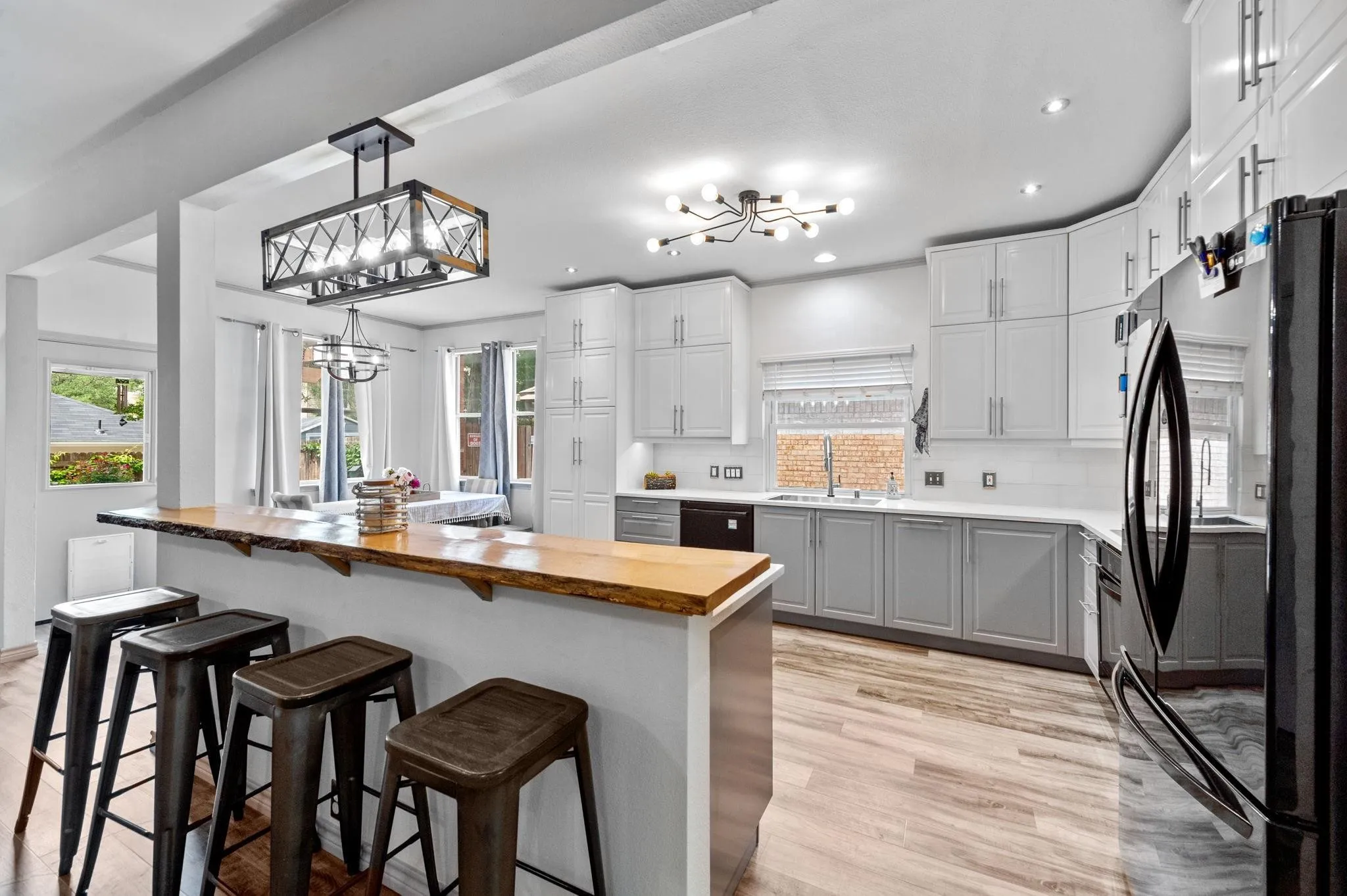 Kitchen featuring a wood-finish breakfast bar, white shaker-style upper cabinetry, gray lower cabinetry, and stainless steel appliances