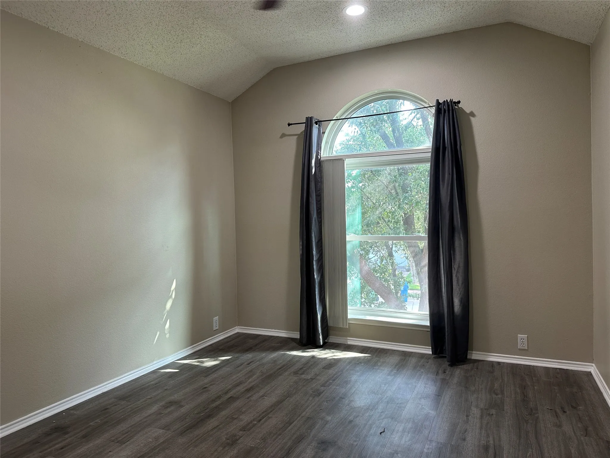 Vaulted ceiling, recessed lighting, arched window, wood-finish flooring