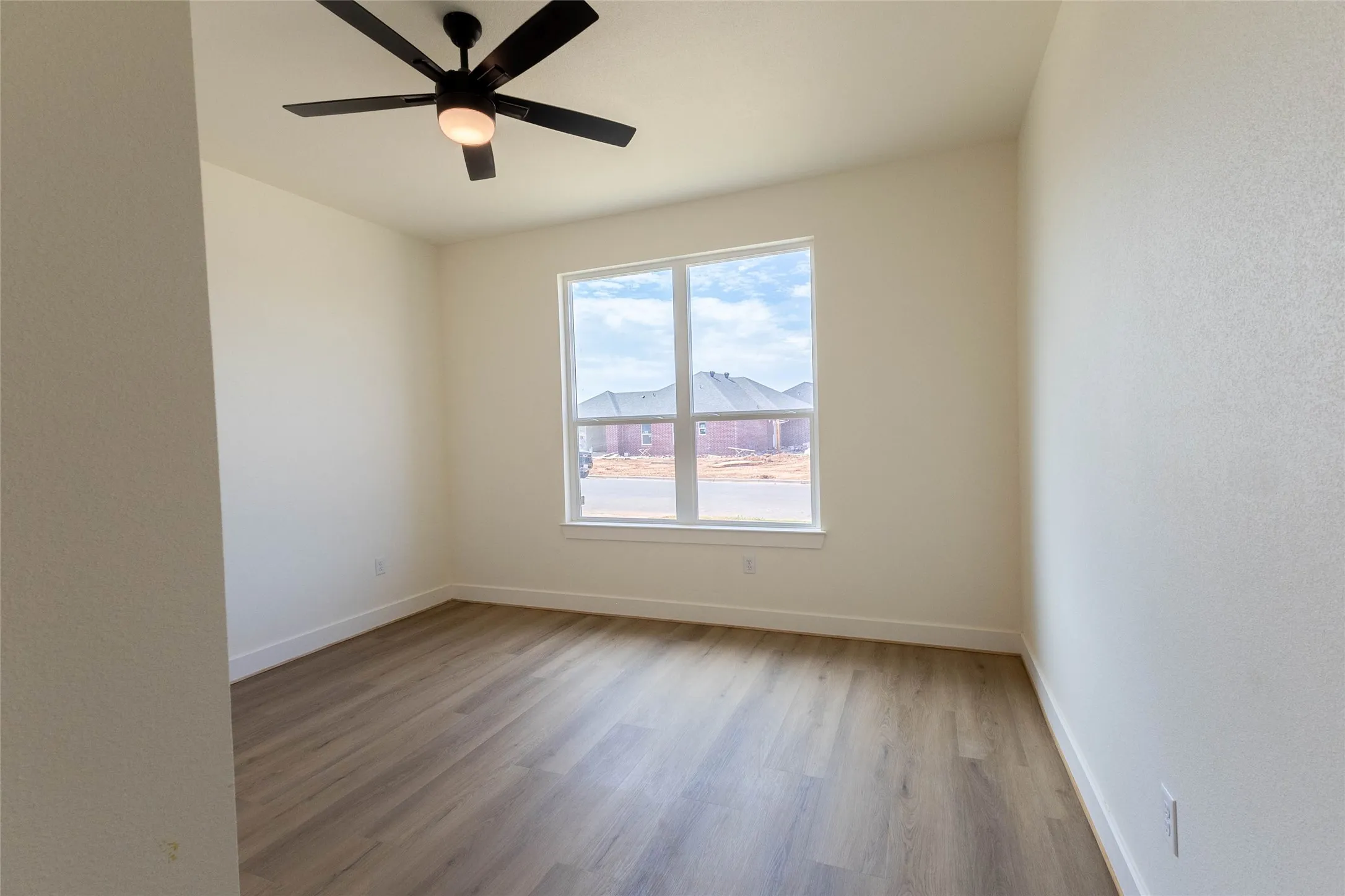 Wood-finish flooring, white walls, and a ceiling fan with integrated lighting