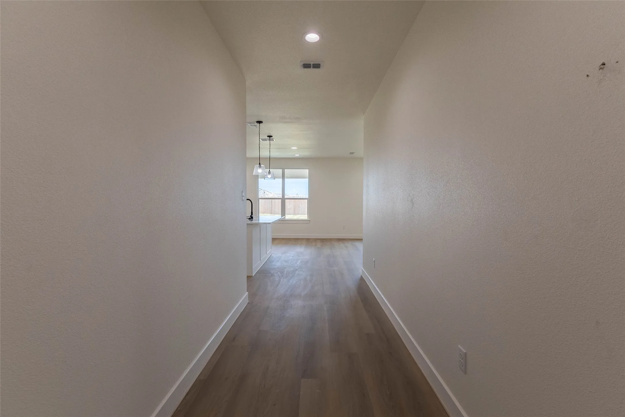 Wood-finish flooring extending into the background, recessed lighting, and a window with natural light