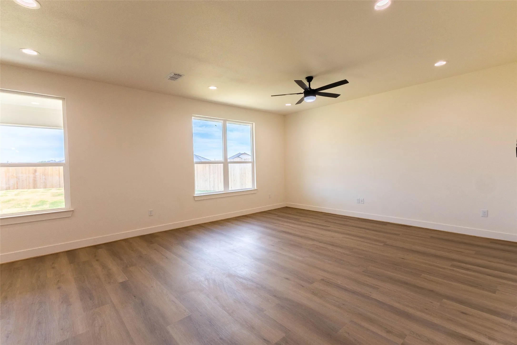 Wood-finish flooring, recessed lighting, ceiling fan, and multiple windows