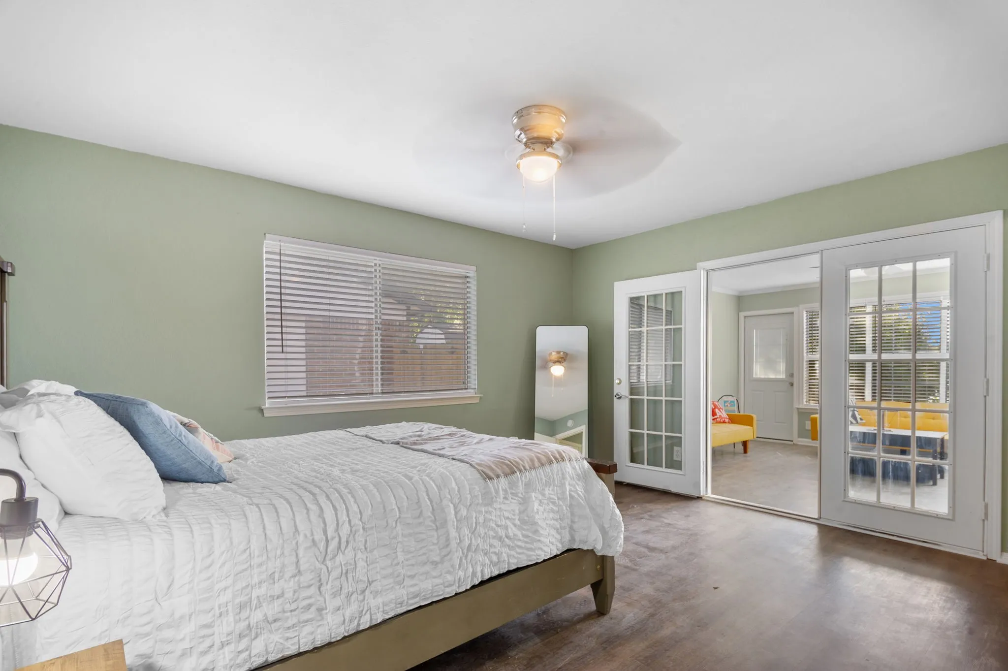 Wood-finish flooring, ceiling fan with integrated lighting, window with horizontal blinds, and double glass-paned doors