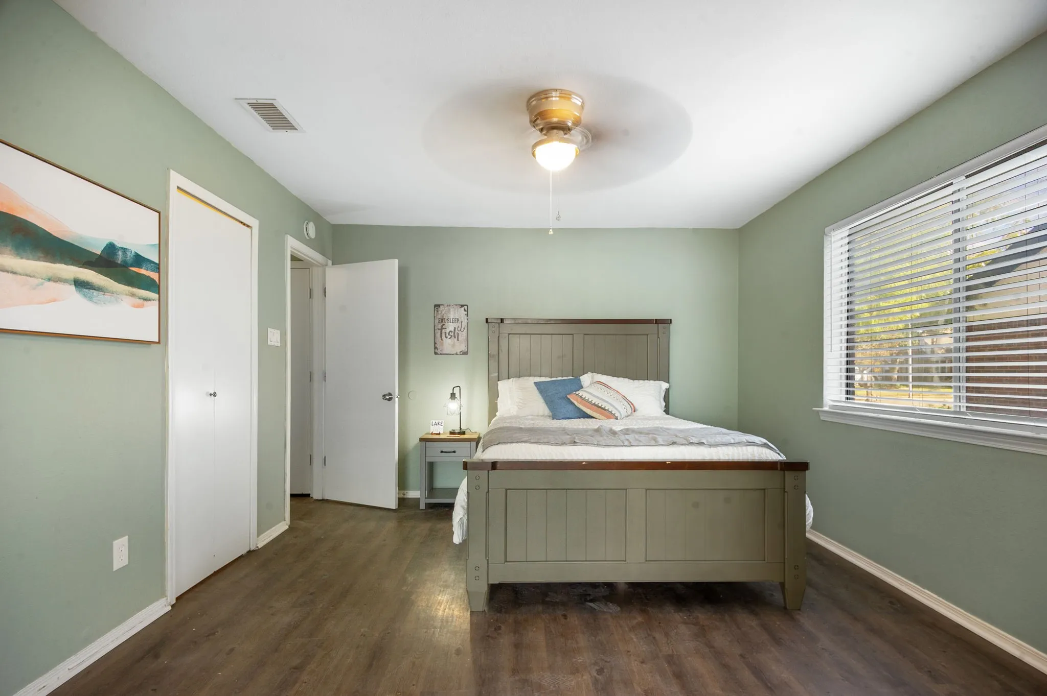 Hardwood-look flooring, ceiling fan, window with blinds, and white doors