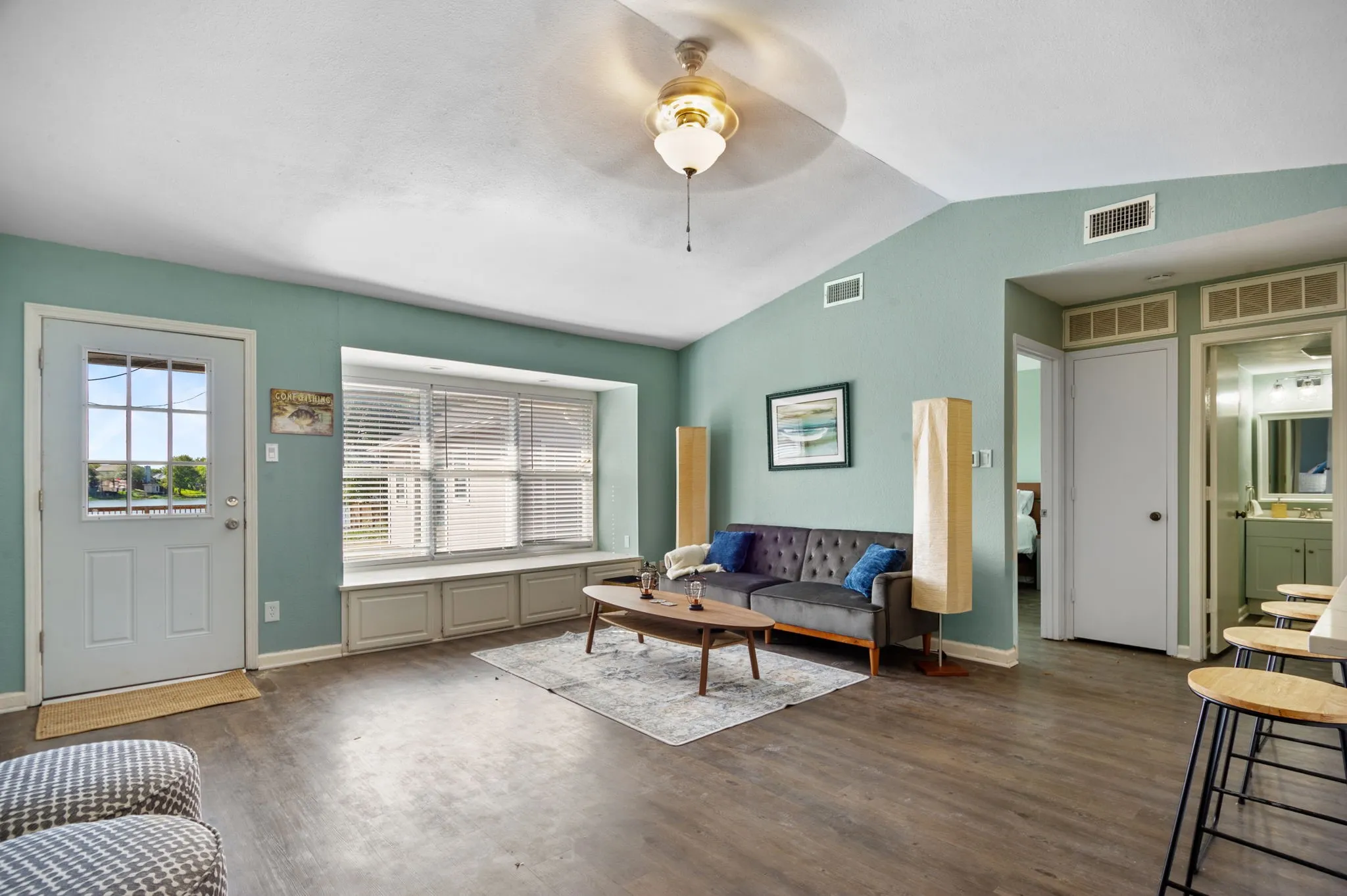 Vaulted ceiling, wood-finish flooring, built-in window seating, transom windows, and an exterior glass-panel door
