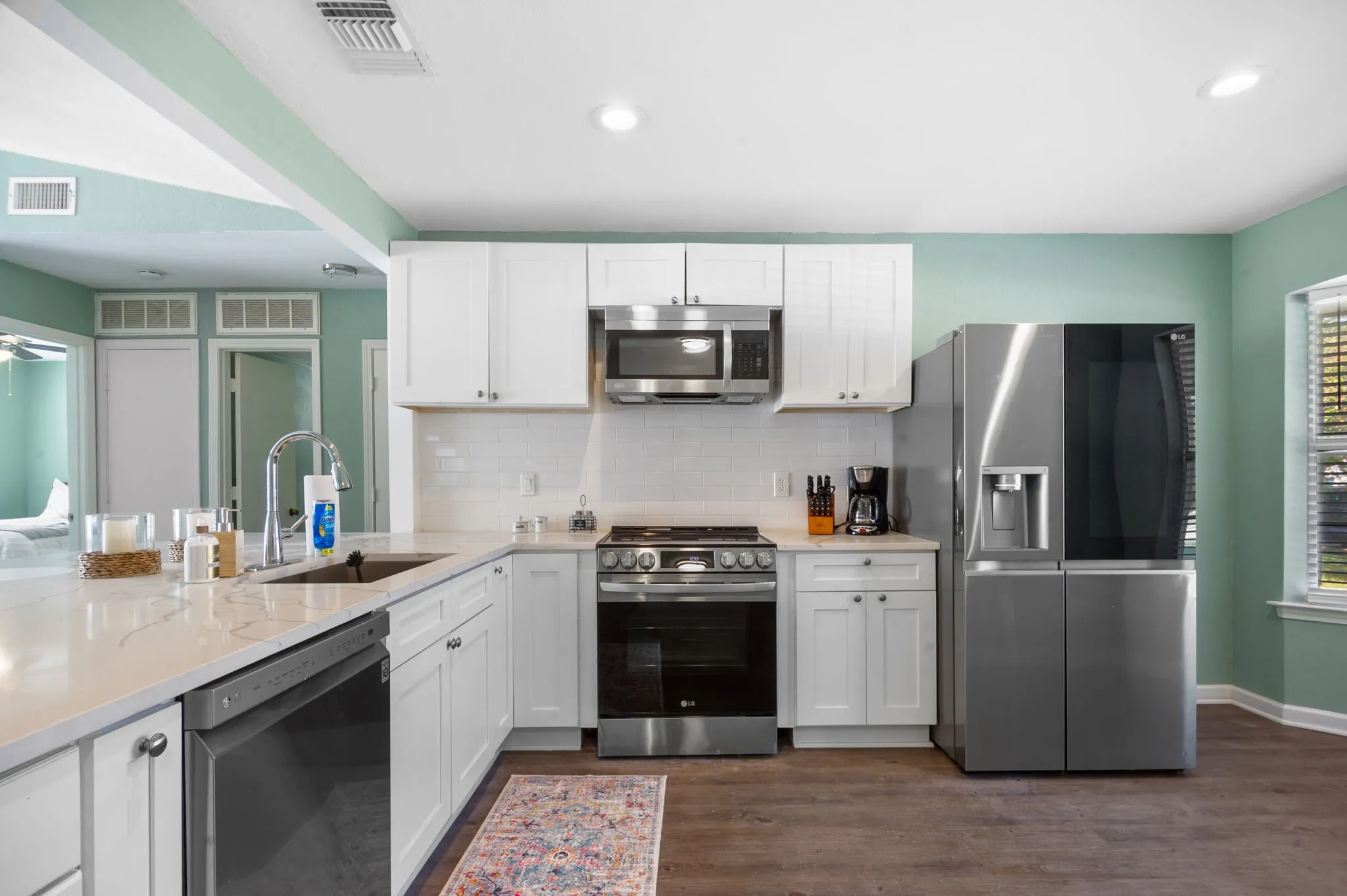 White shaker cabinetry with stainless steel appliances, white quartz countertops, and a subway tile backsplash