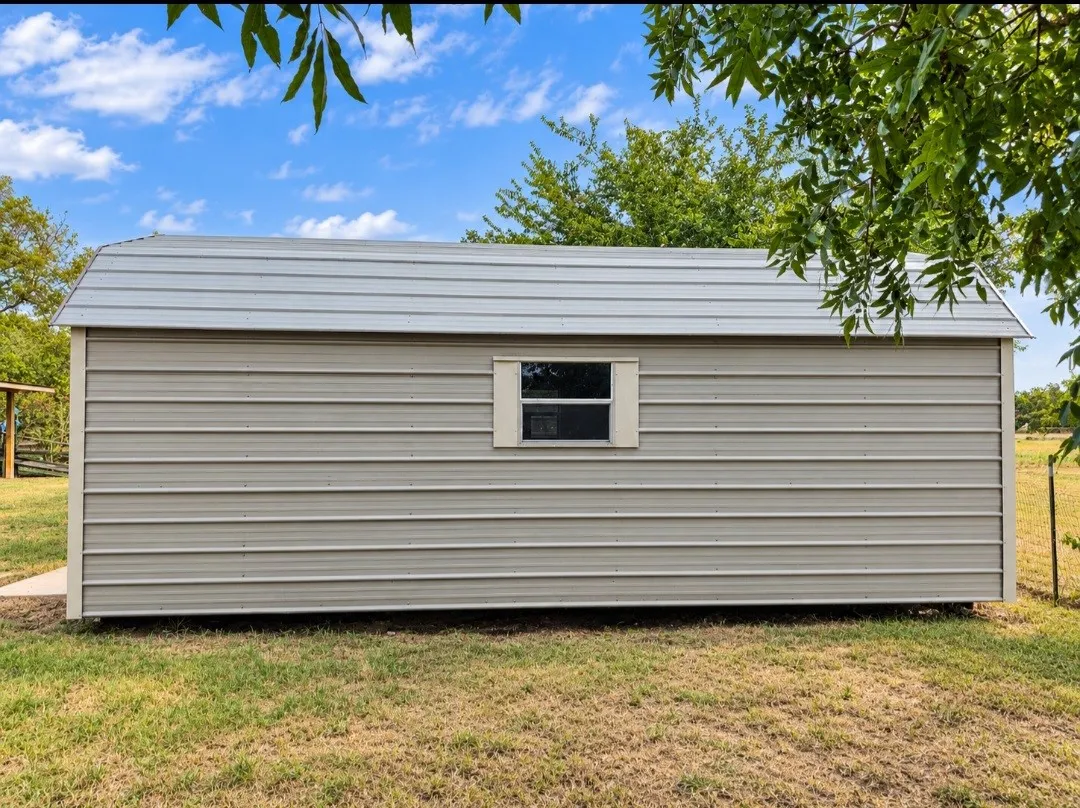 Metal-sided outbuilding featuring a pitched metal roof and a single window