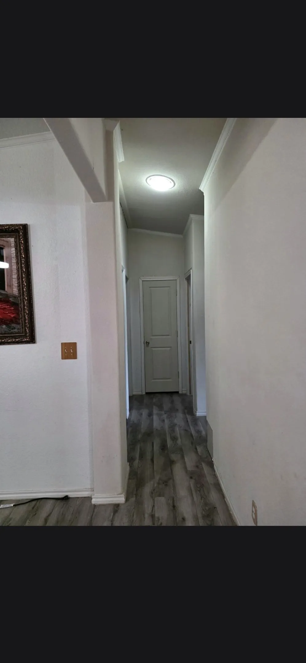 Wood-finish flooring in a neutral tone, recessed ceiling lighting, and crisp white walls