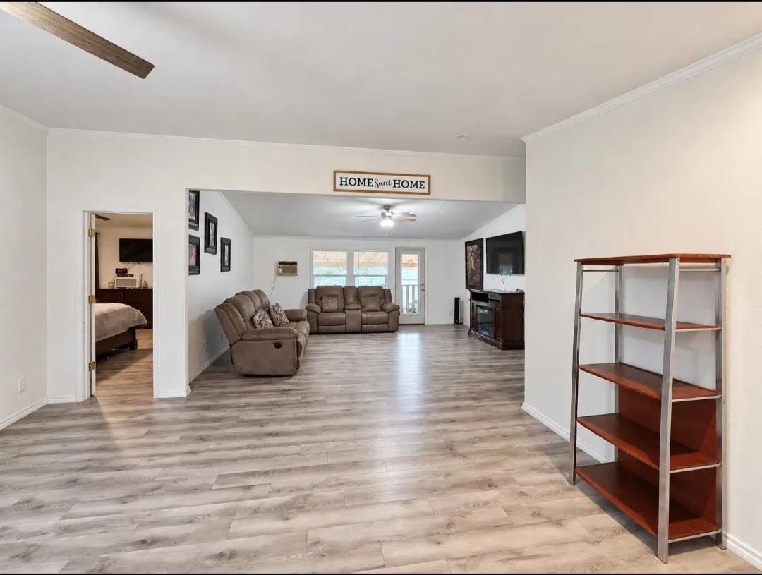 Light wood-finish flooring, white walls, and crown molding