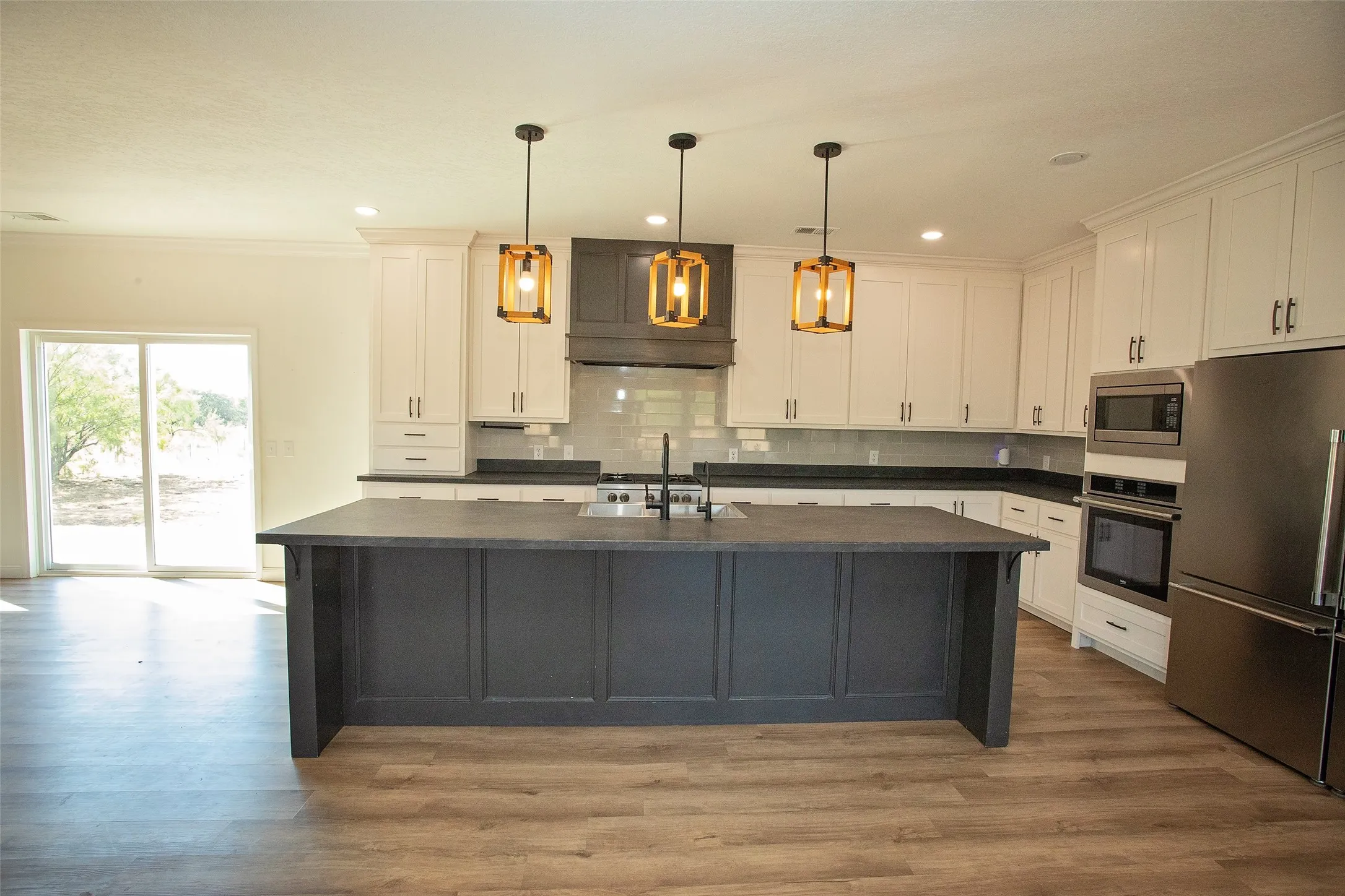 Gourmet kitchen featuring a large central island, white cabinetry, dark countertops, and stainless steel appliances
