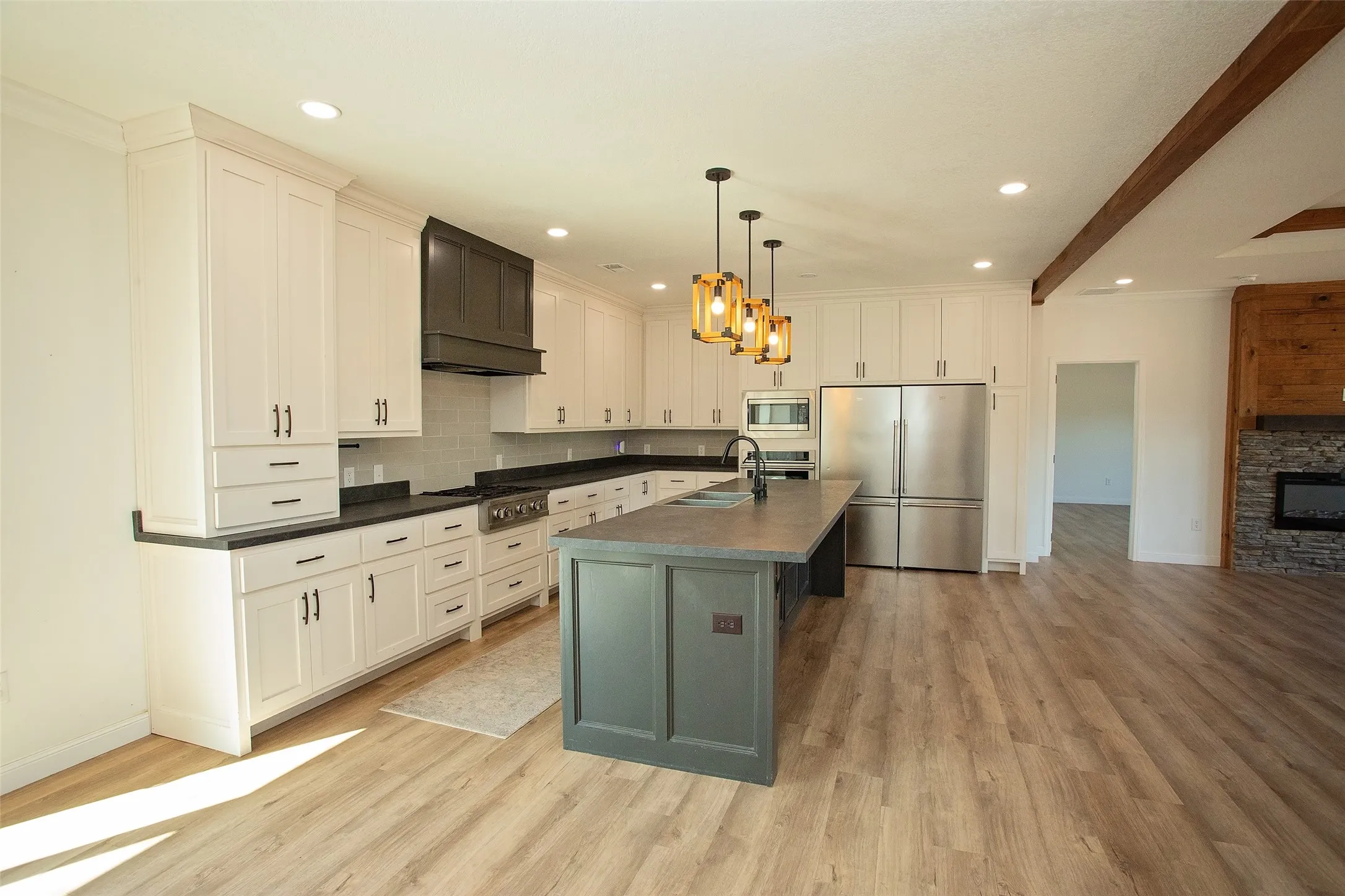 Modern kitchen featuring white shaker cabinetry, dark countertops, a dark-toned kitchen island, and light wood-finish flooring