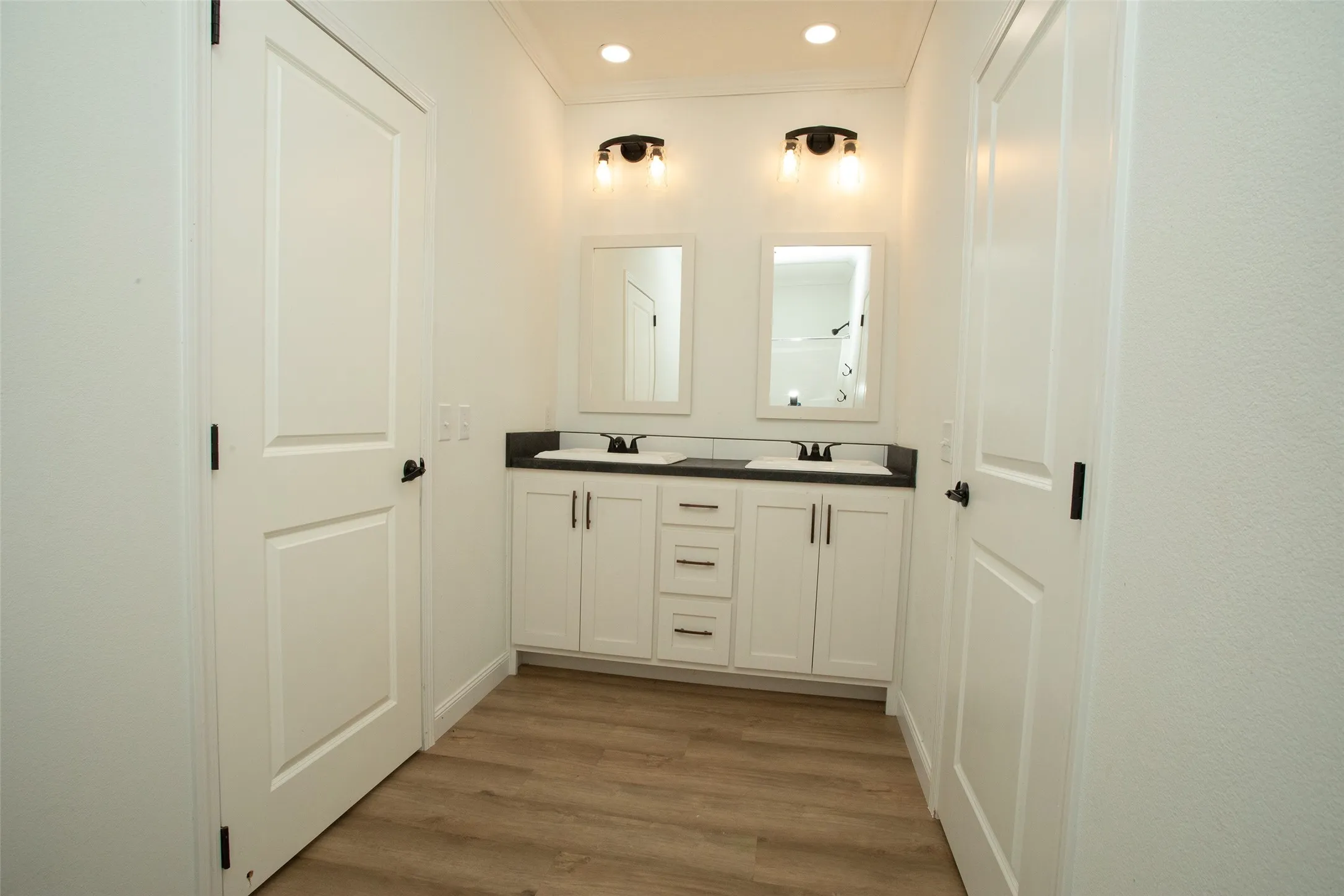 Double vanity with white cabinetry, dark countertops, and undermount sinks