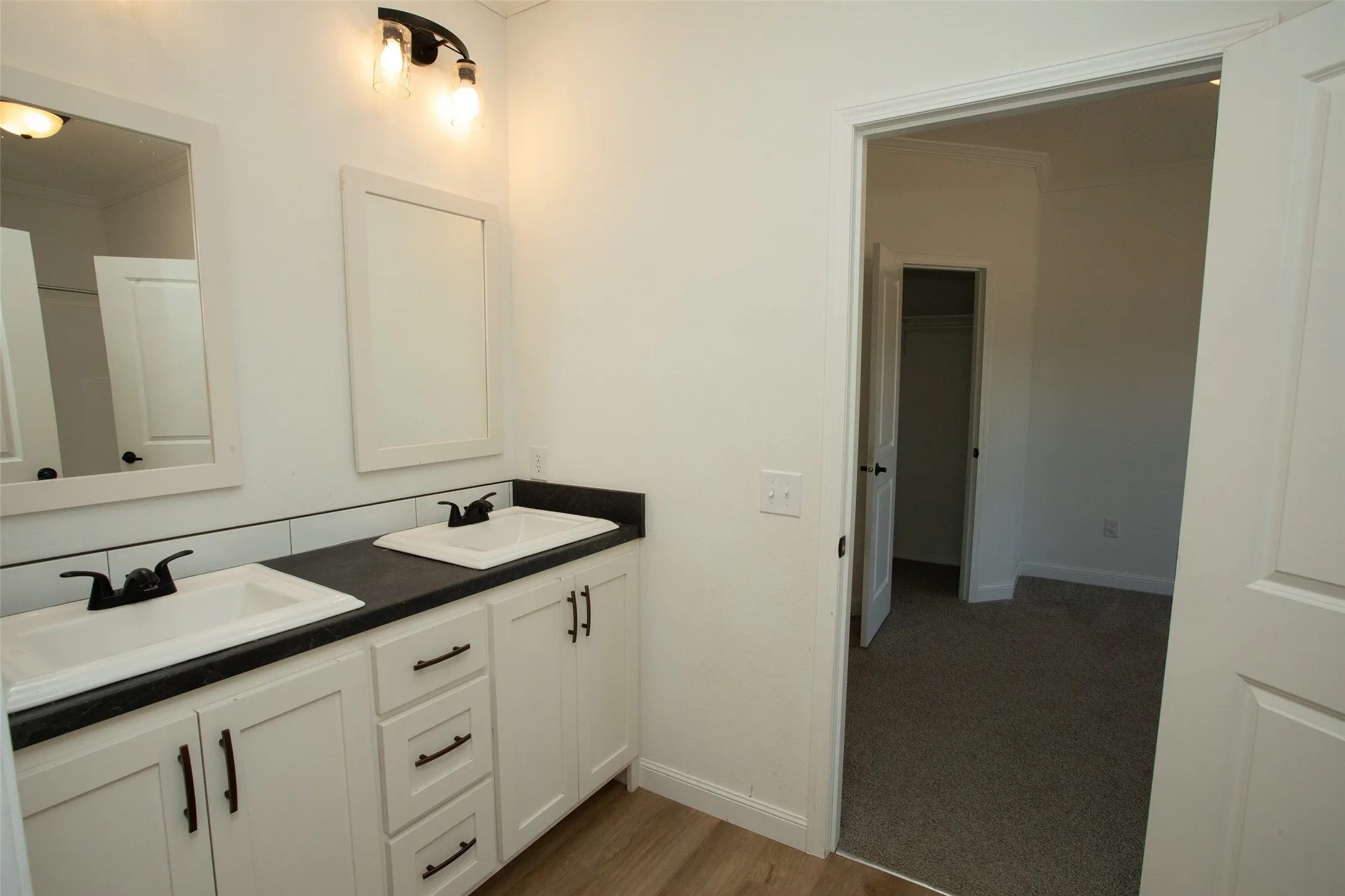 Dual vanity with white cabinetry, matte black hardware, and black countertops