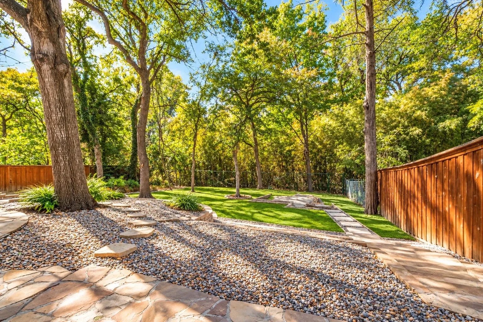 Digitally enhanced - Expansive backyard featuring mature trees, flagstone patio, gravel landscaping, a stepping stone path, and a wooden privacy fence