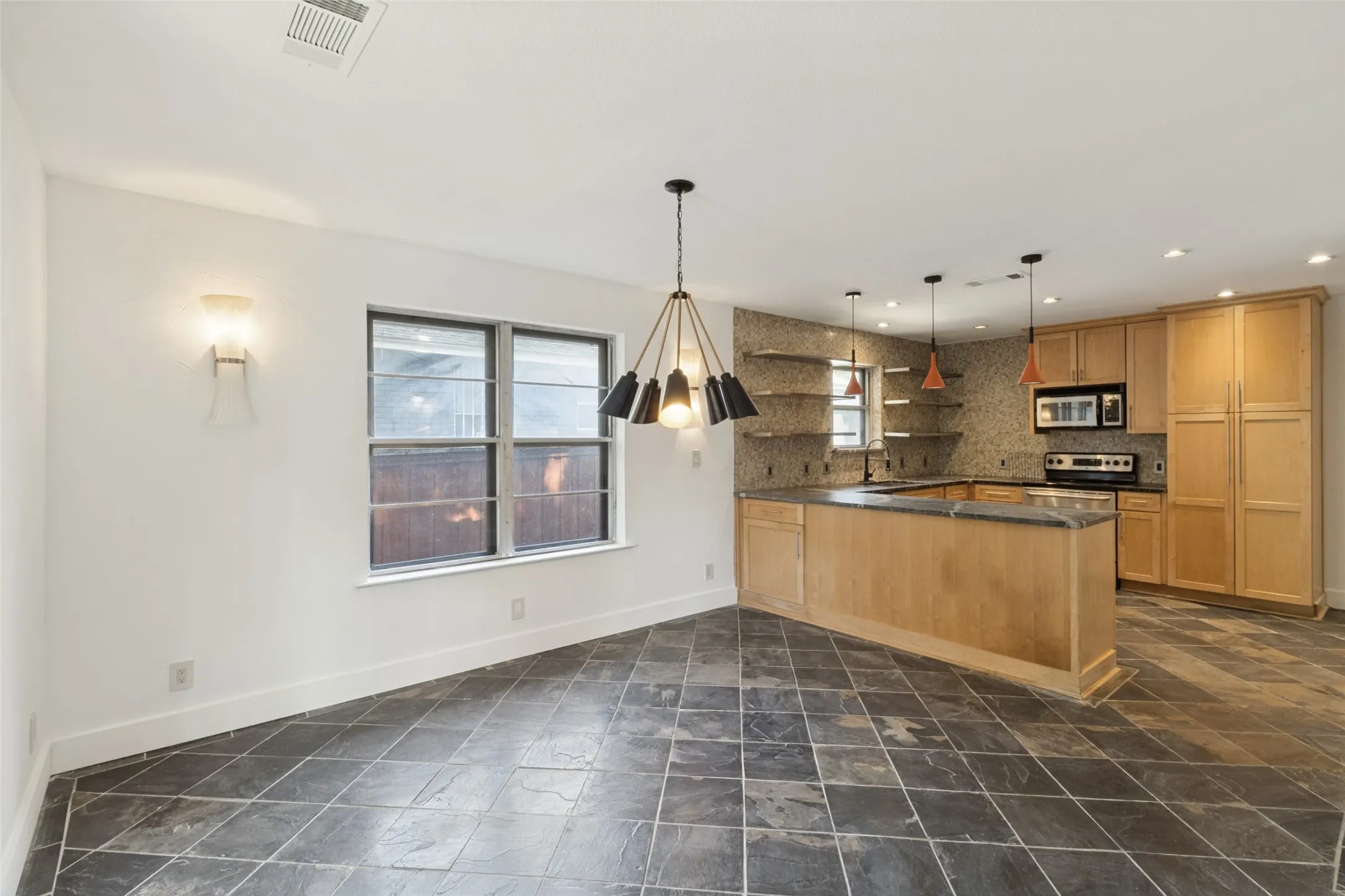 Kitchen with wood cabinetry, stainless steel appliances, open shelving, and pendant lighting