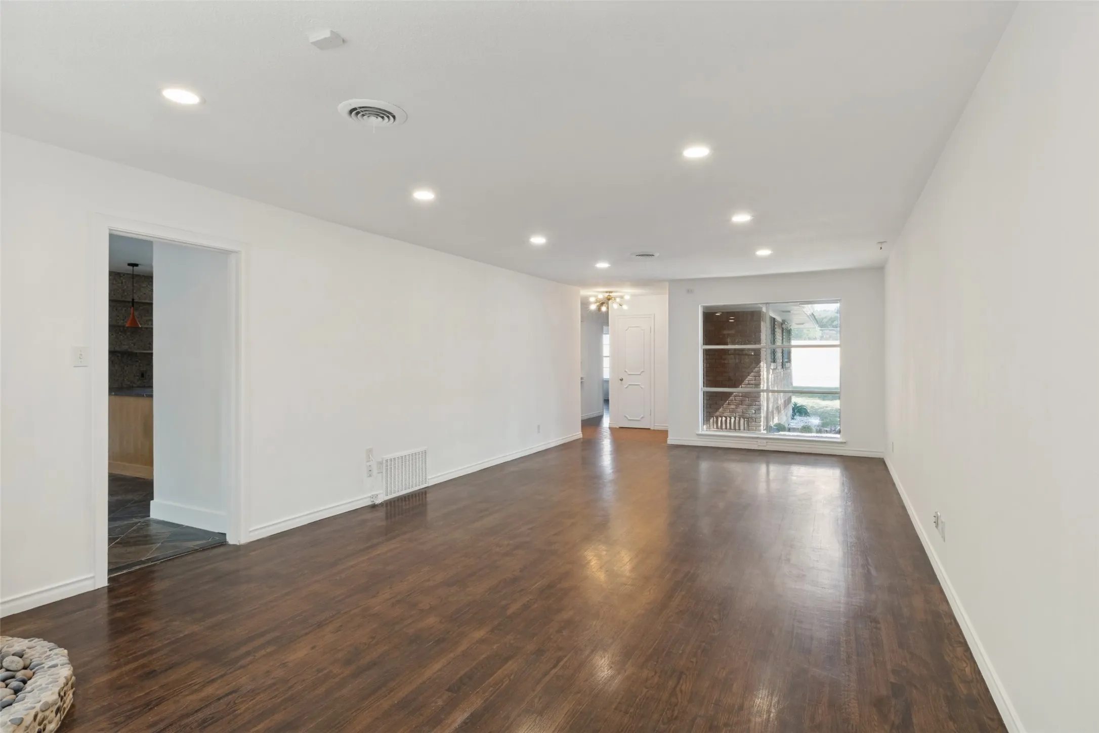 Spacious room with recessed lighting, wood-finish flooring, and a large window