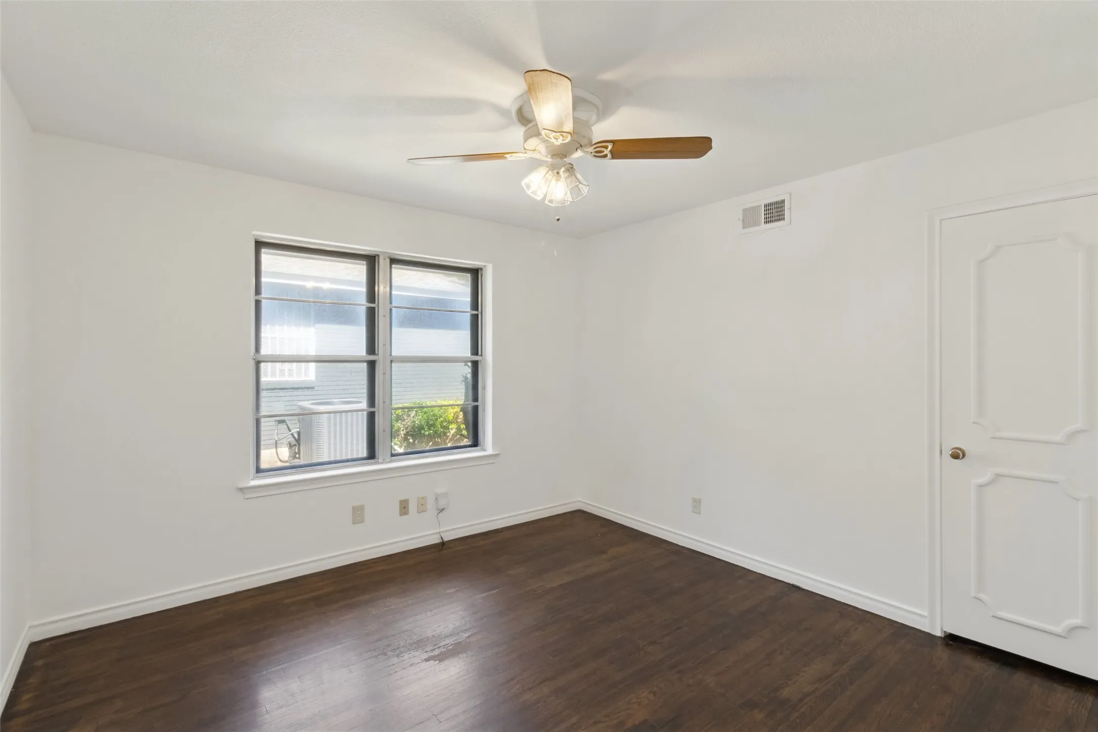 Dark wood-finish flooring, white walls, and a multi-panel door