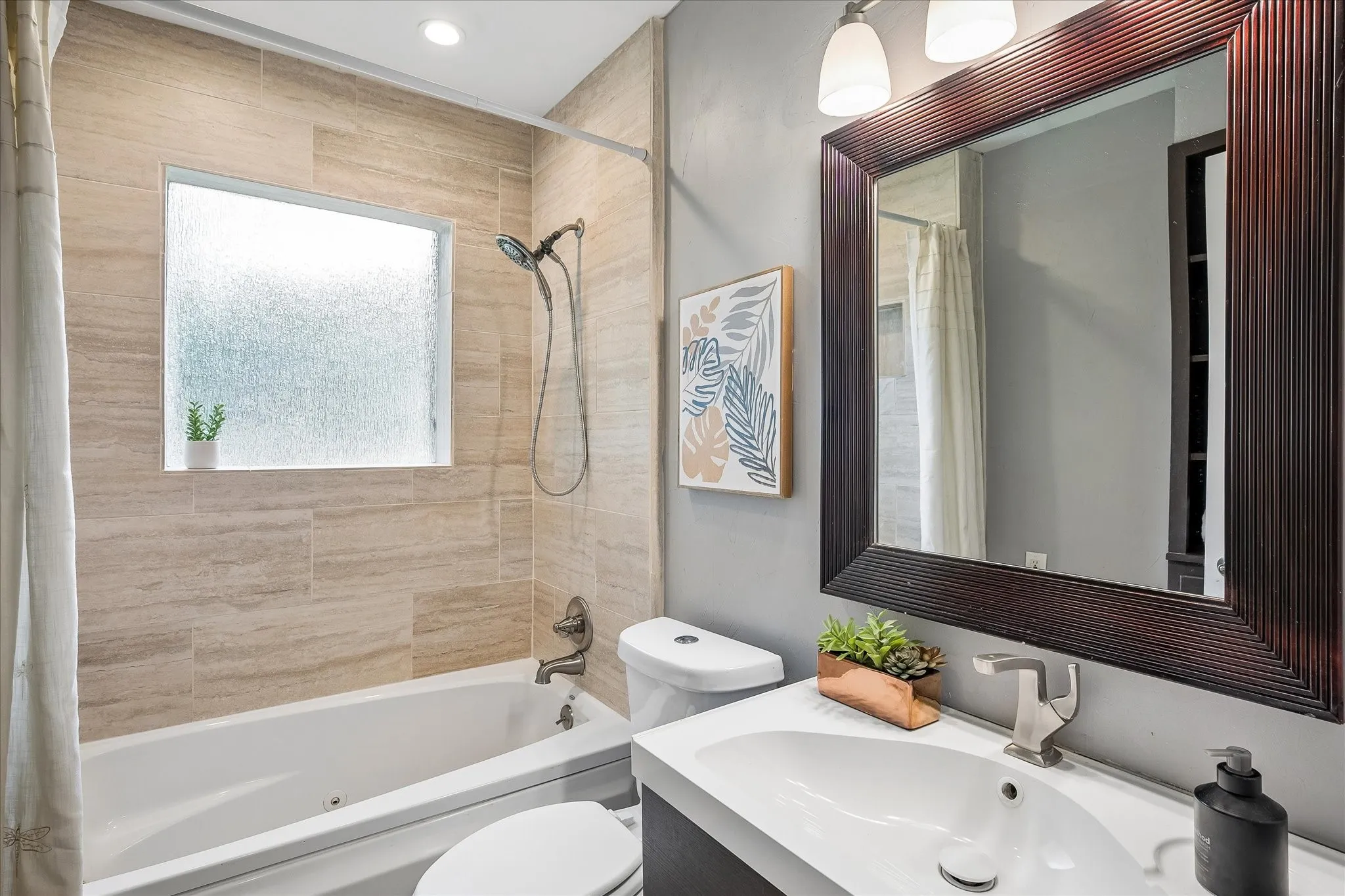 Fully renovated bath with jetted tub , full tile shower surround and frosted glass window.