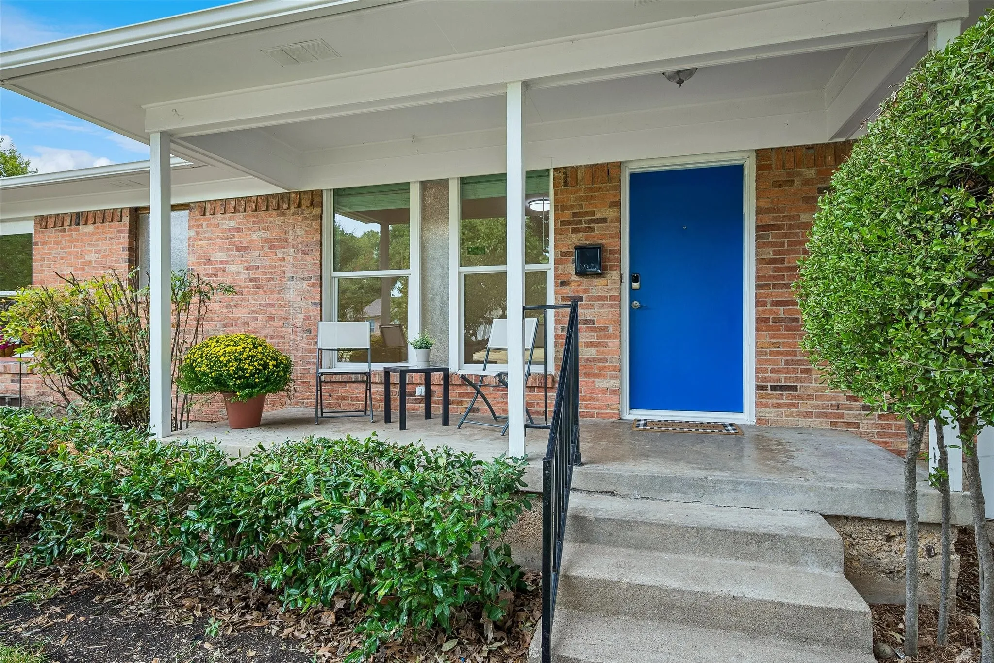 Welcoming covered front porch with colorful front door that pops!