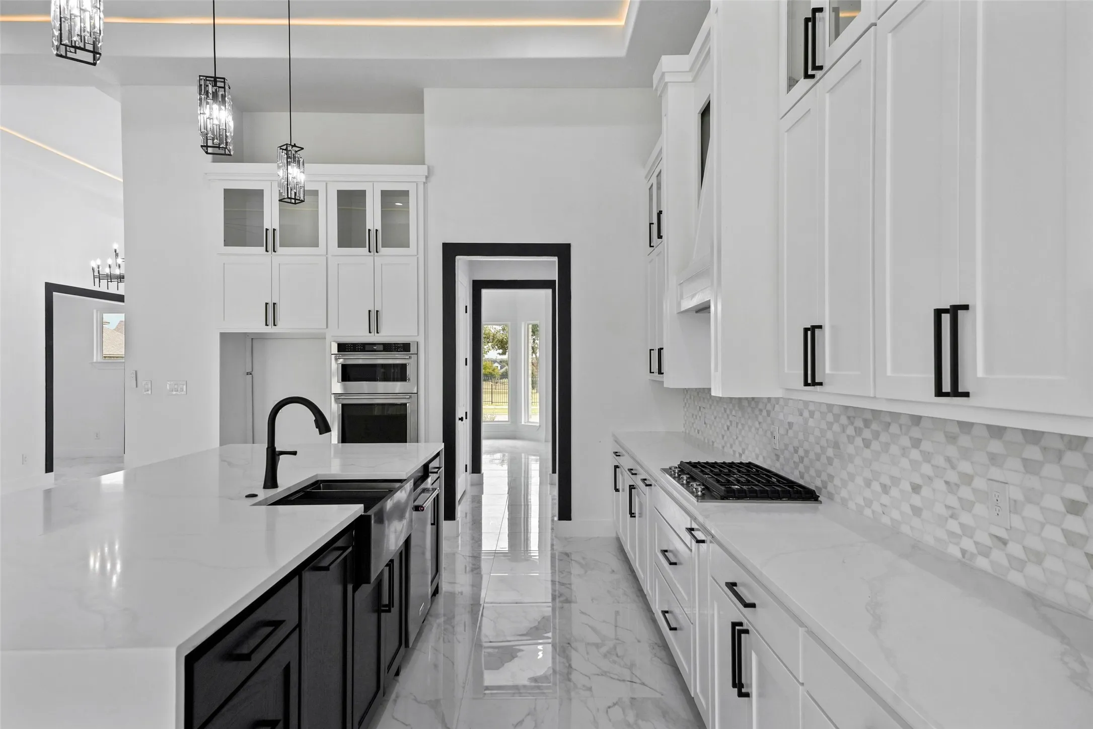 White cabinetry with black hardware, white countertops, built-in stainless steel appliances, and a mosaic tile backsplash