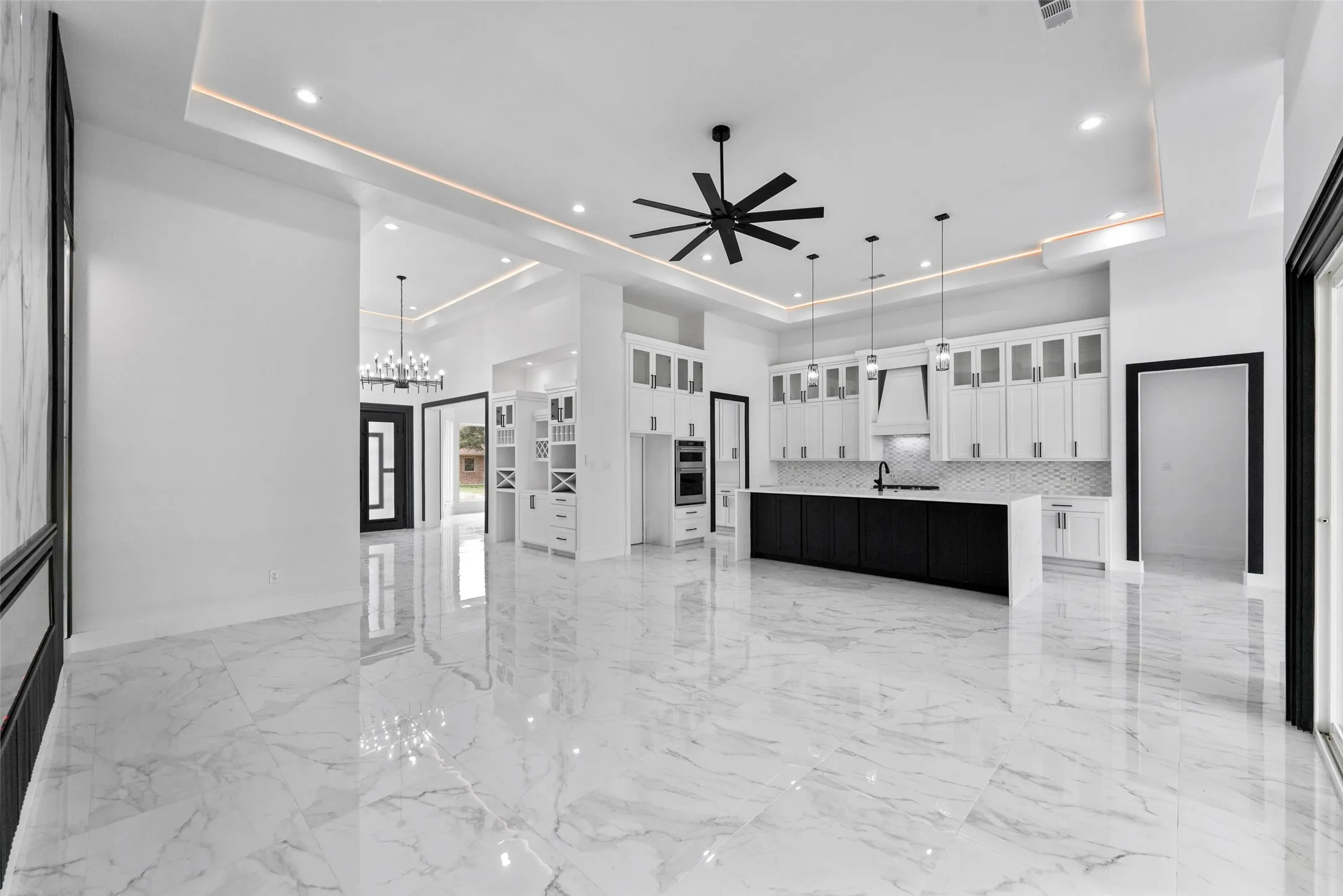 Open-concept living area featuring large format marble-look tile flooring, a contemporary kitchen with a large island, stainless steel appliances, and abundant cabinetry