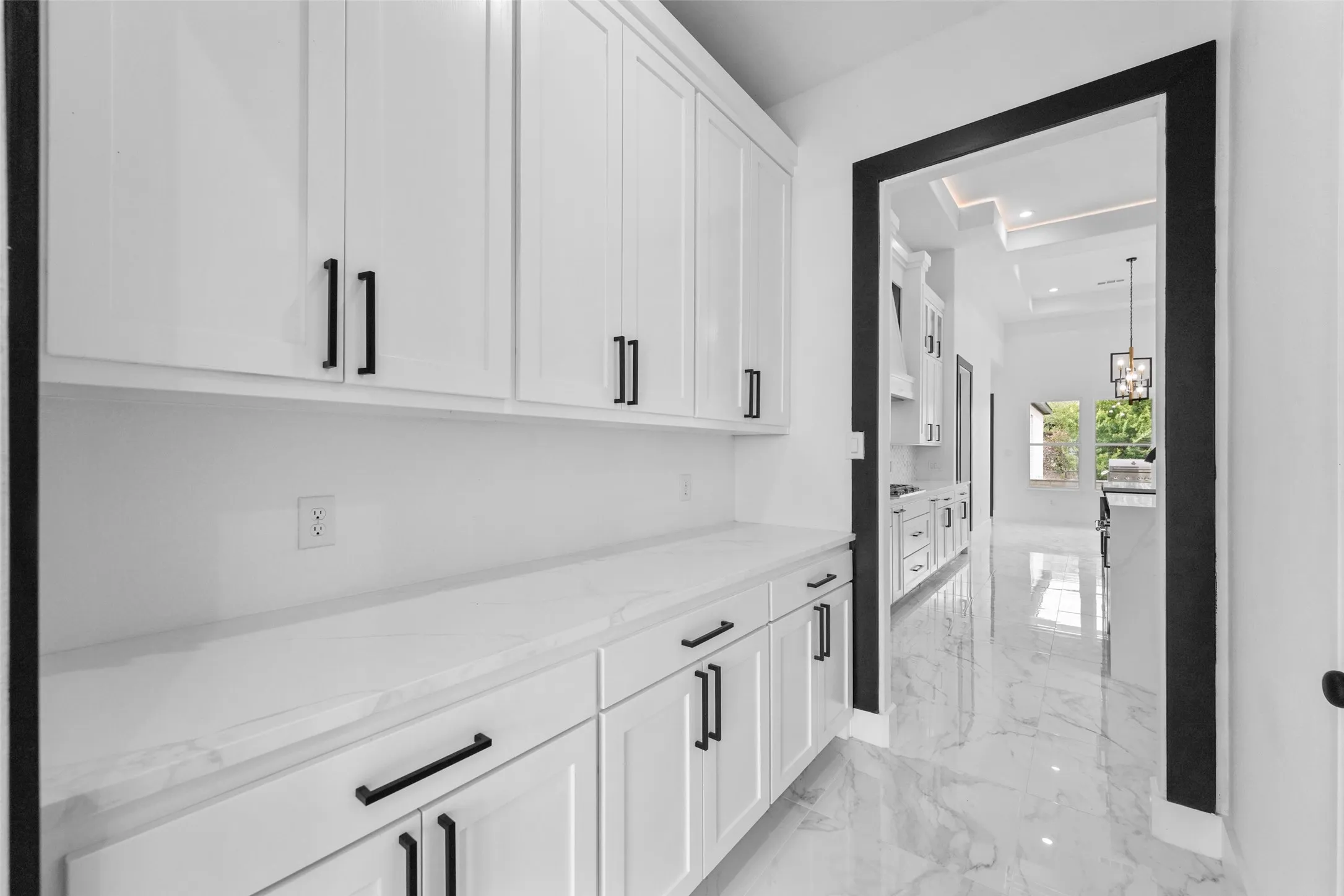 White cabinetry with black hardware, white countertops, and white marble-finish flooring