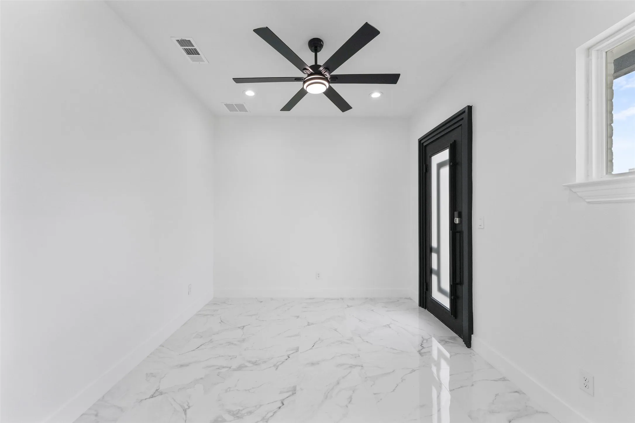 White walls, large format tile flooring, black ceiling fan with integrated lighting, recessed lighting, and a black framed door with glass inserts