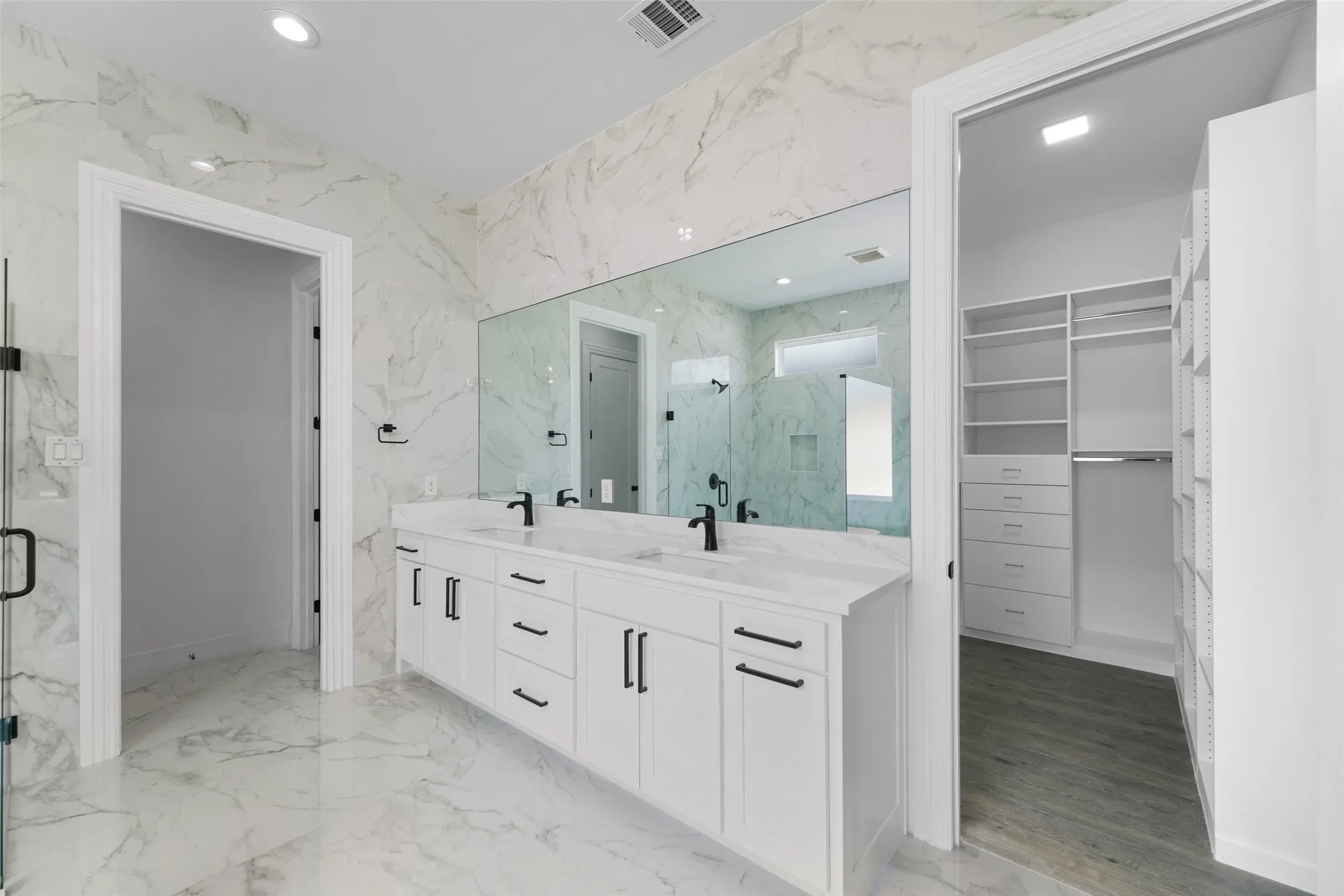 Dual vanity with white cabinetry, matte black hardware, and an expansive mirror