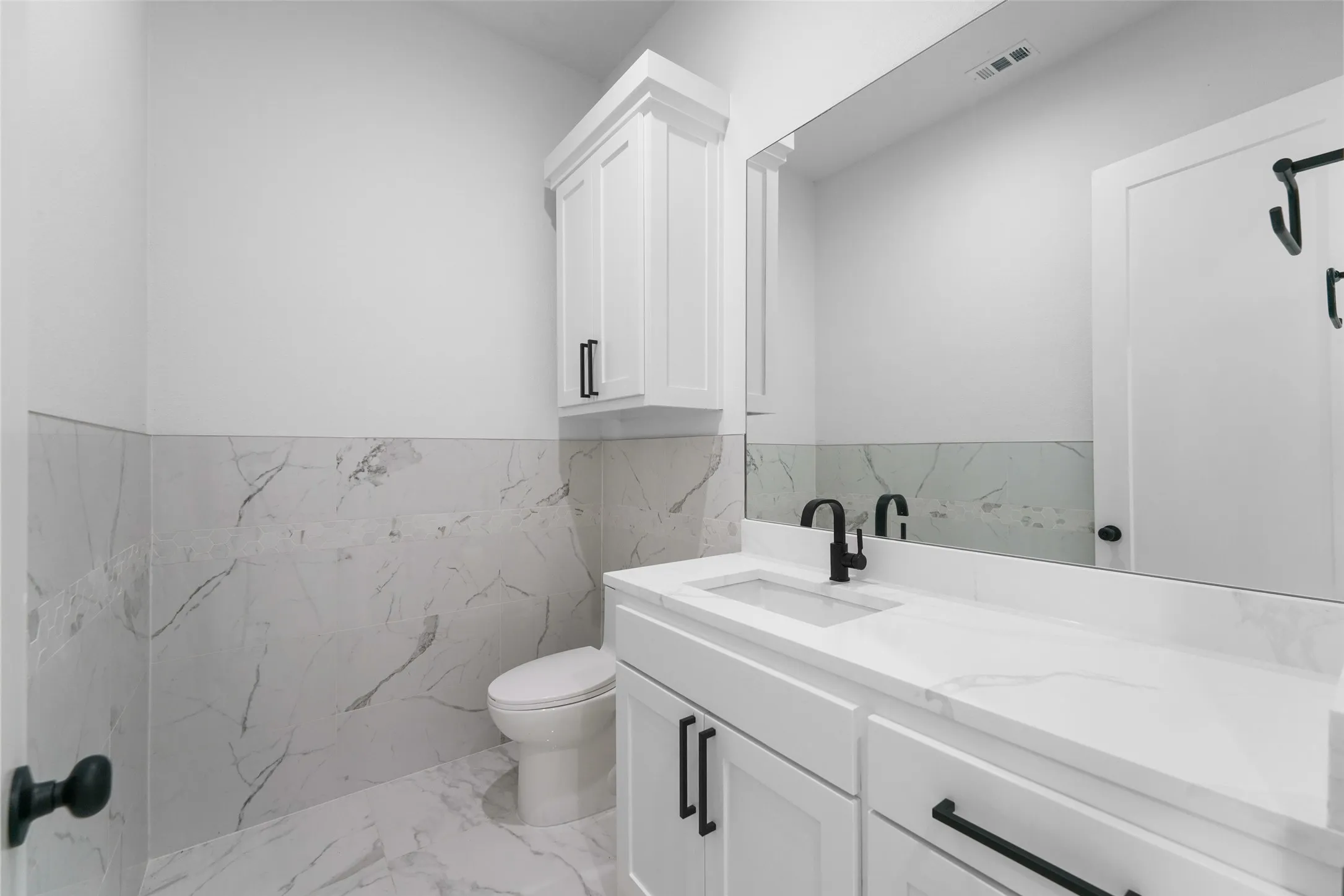White shaker vanity with integrated sink, black matte faucet, and a large wall-mounted mirror