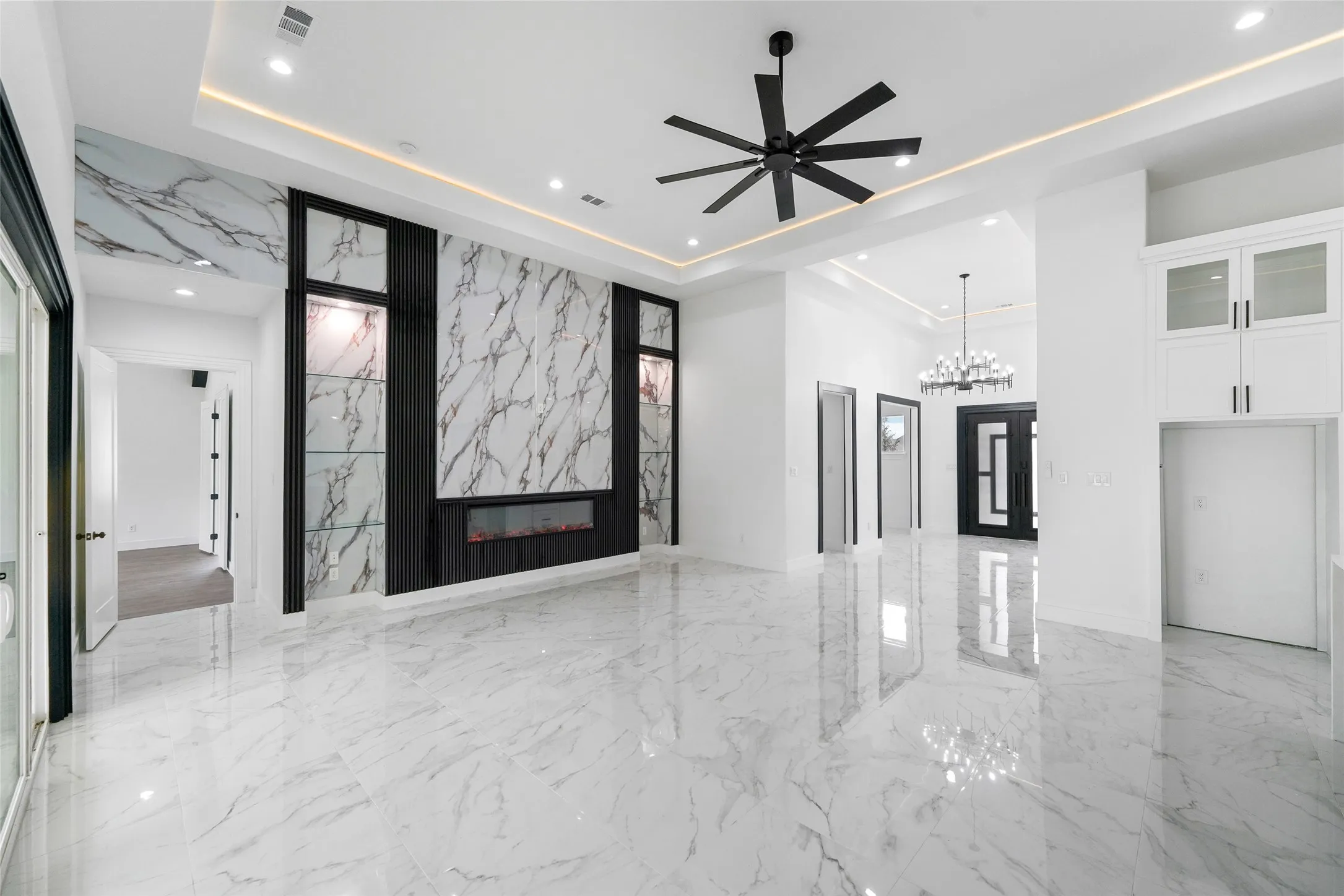 Polished large format tile flooring, recessed lighting, accent wall with integrated linear fireplace, built-in shelving with accent lighting, and a ceiling fan