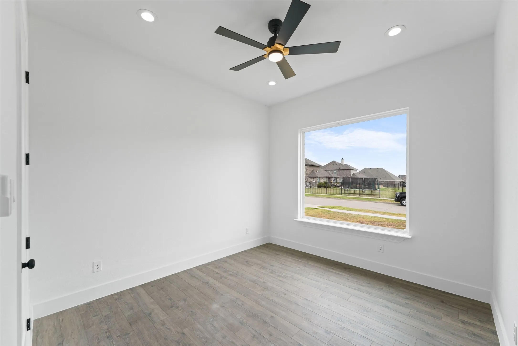 Recessed lighting, ceiling fan with light fixture, large window, wood-finish flooring, and white baseboards