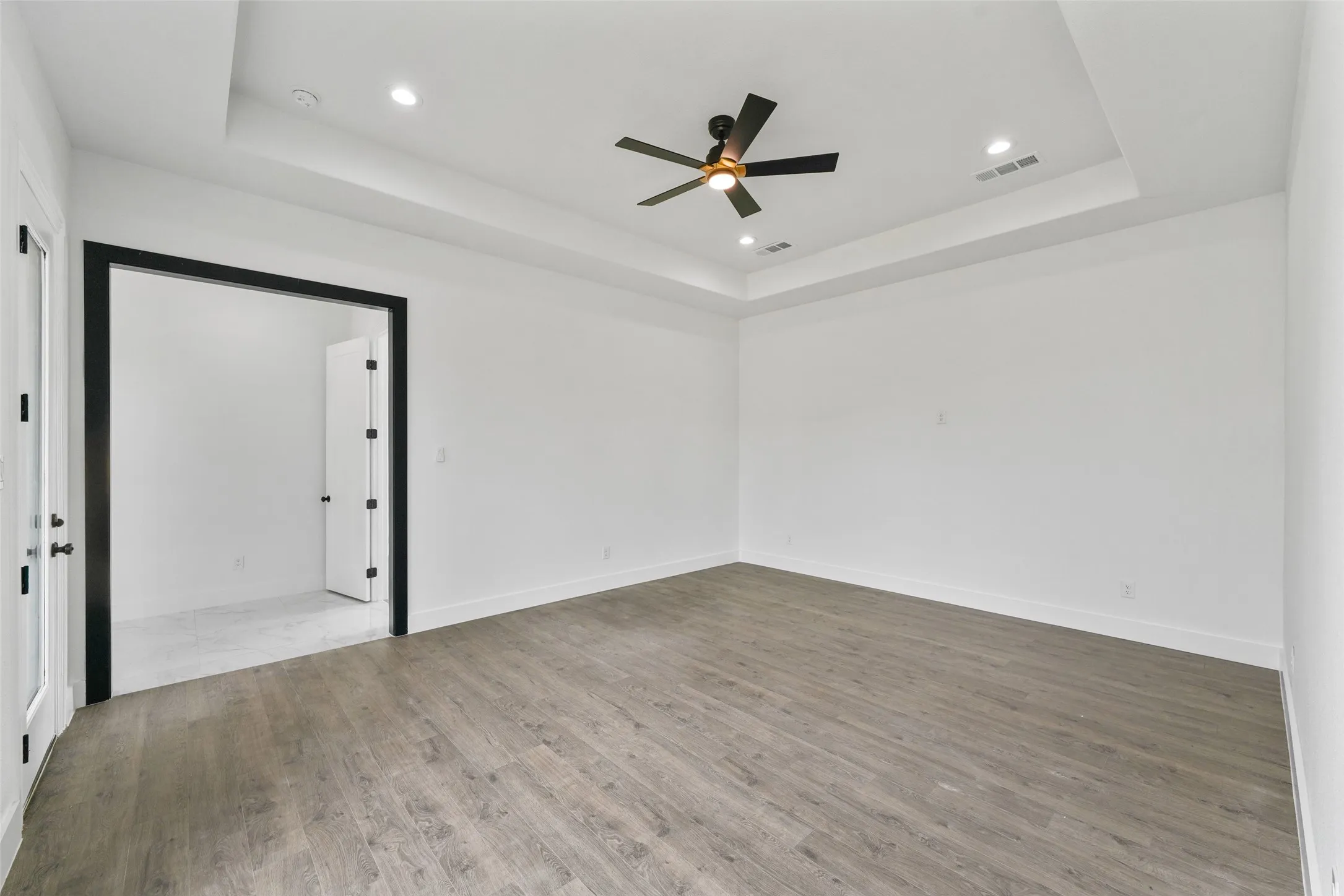 Tray ceiling with recessed lighting, wood-finish flooring, and a ceiling fan