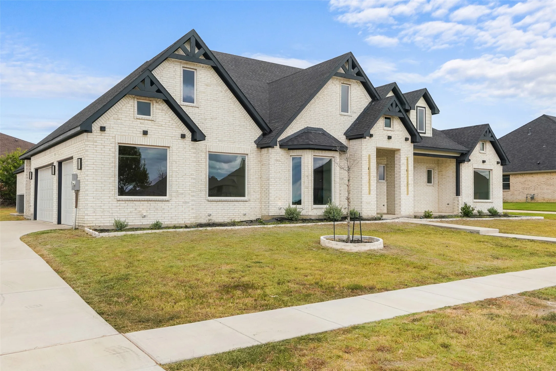 Brick exterior with dark trim accents, multiple gables, a two-car garage, and bay windows