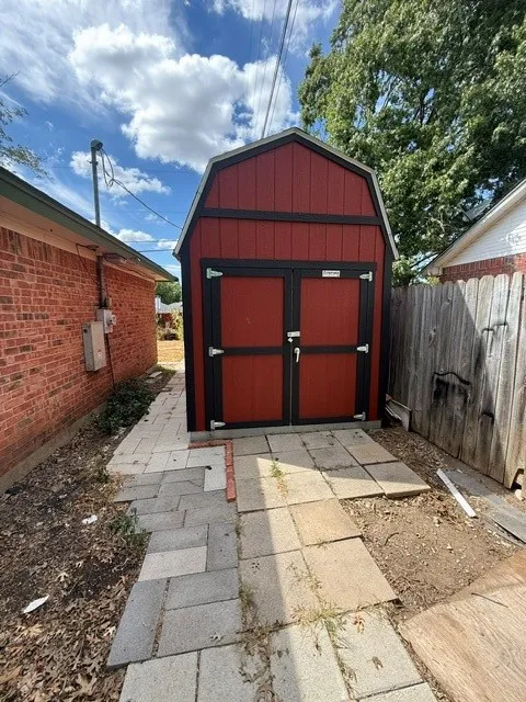 Barn-style storage shed with double doors and black trim