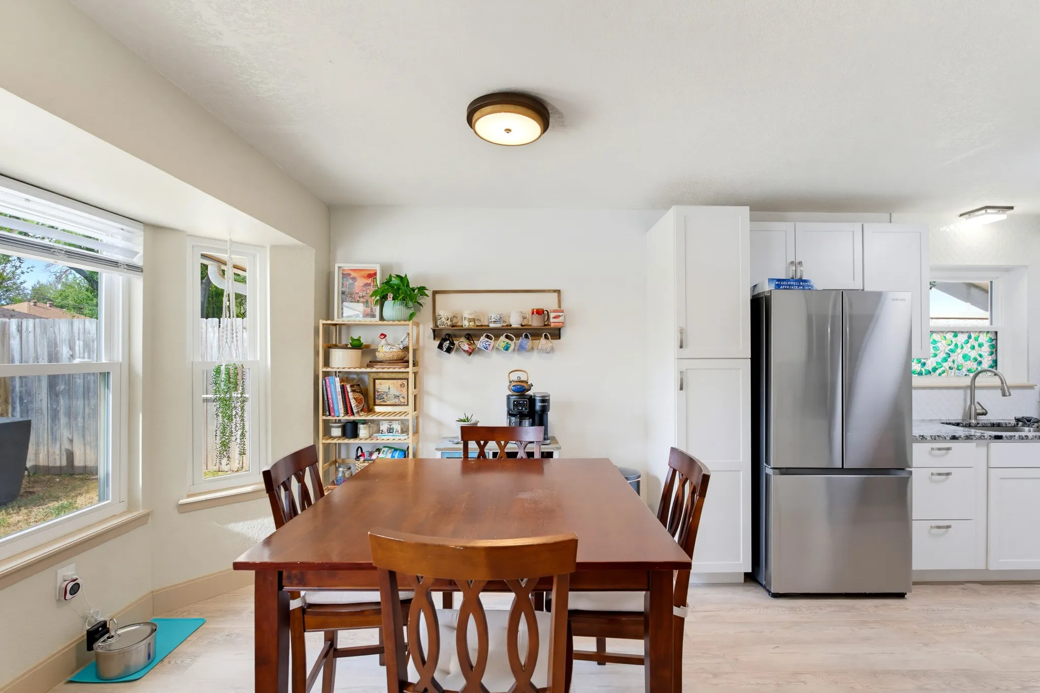 Bay window with multiple panes, recessed lighting, wood-finish flooring, white cabinetry, stainless steel French door refrigerator