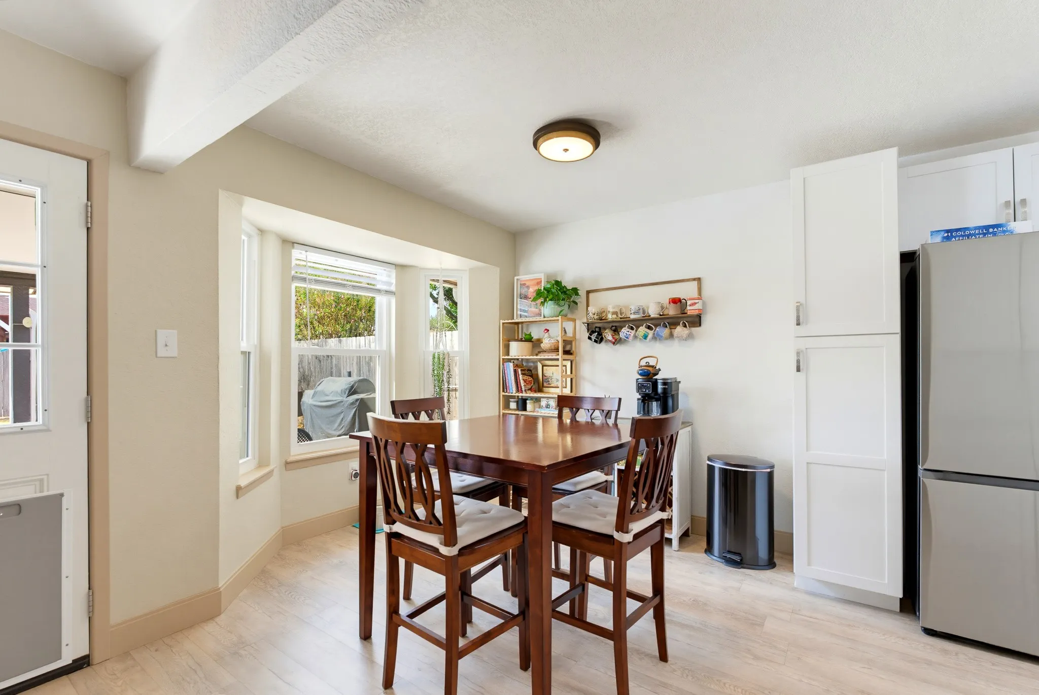 Light wood-finish flooring, bay windows, and white cabinetry
