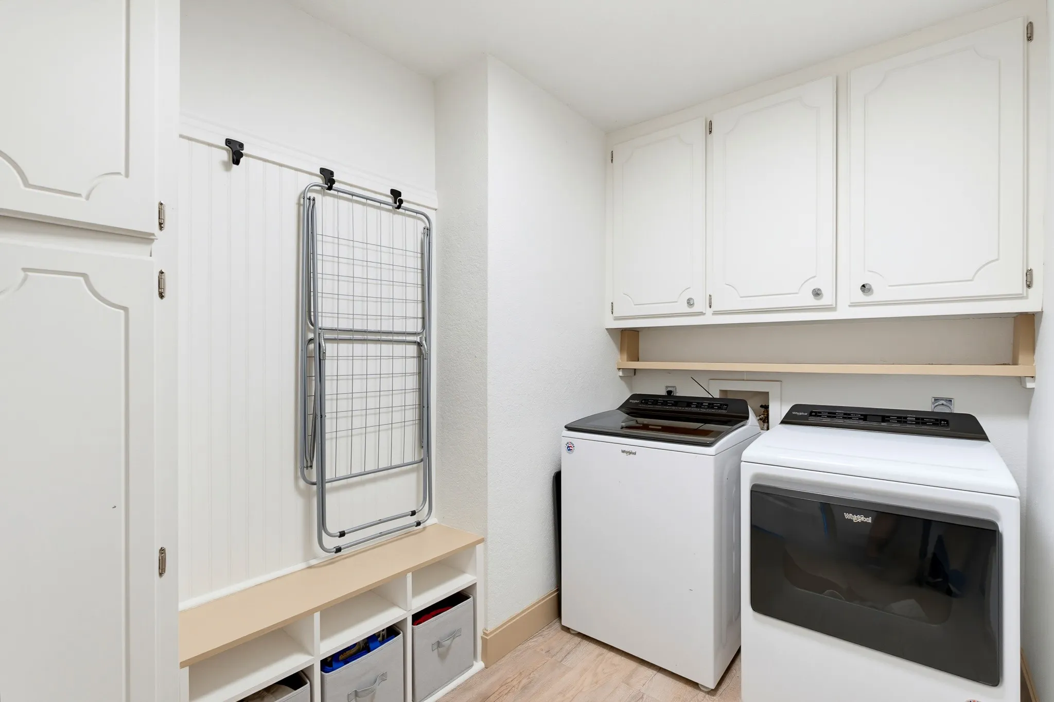 White cabinetry, beadboard paneling, light wood-finish flooring, and built-in storage cubbies