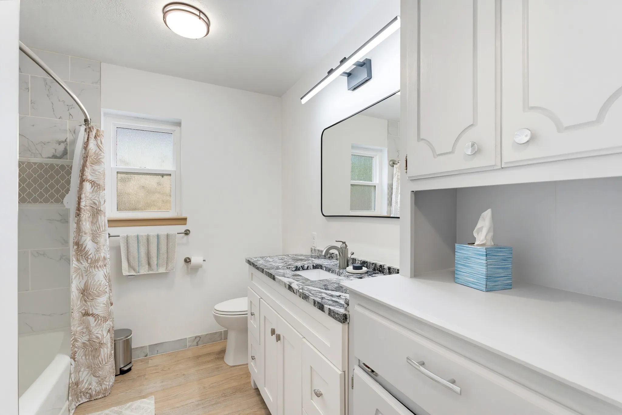 White vanity with a dark stone countertop, undermount sink, and polished chrome faucet