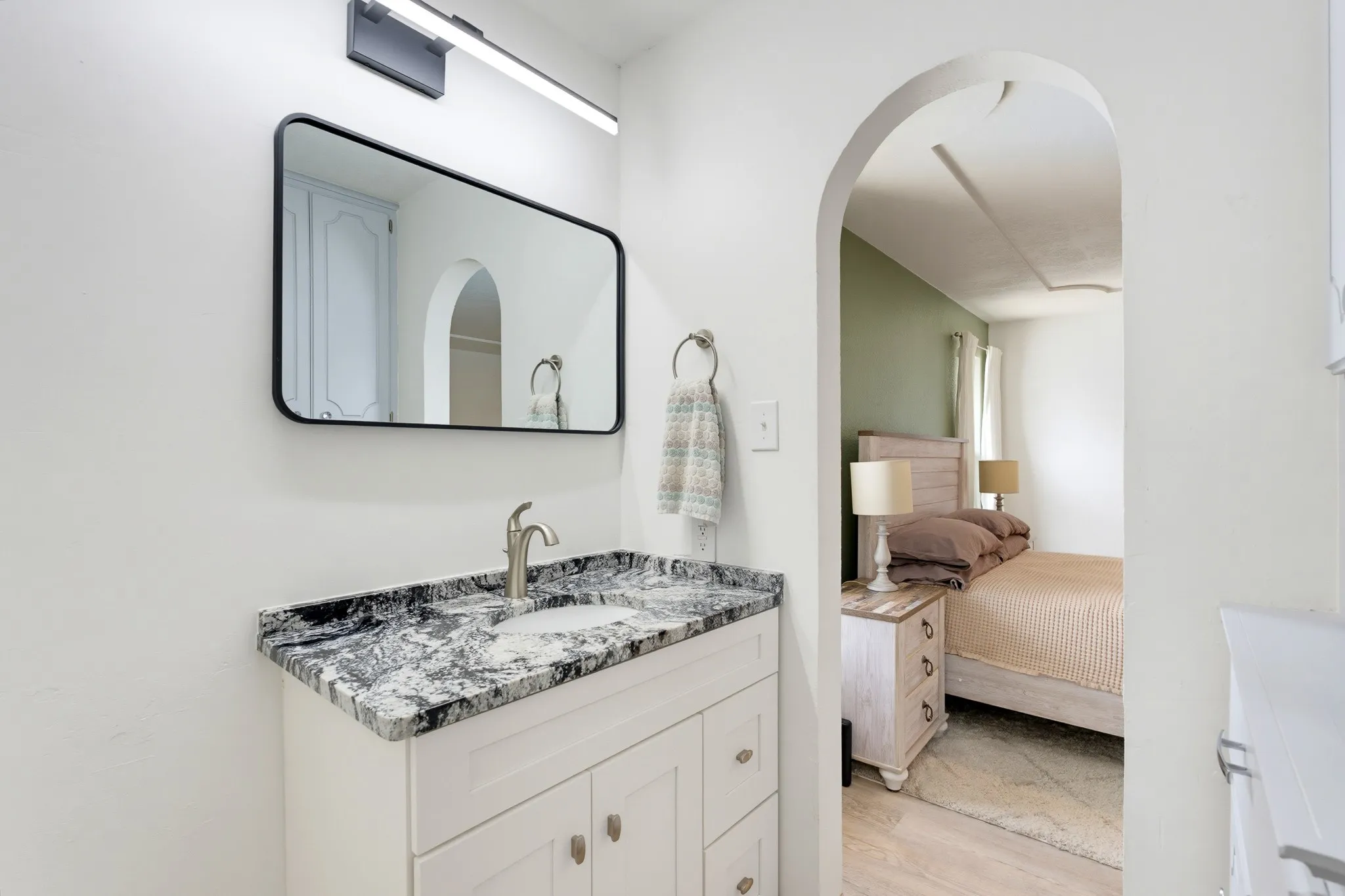 White vanity with a granite countertop, undermount sink, and brushed nickel faucet