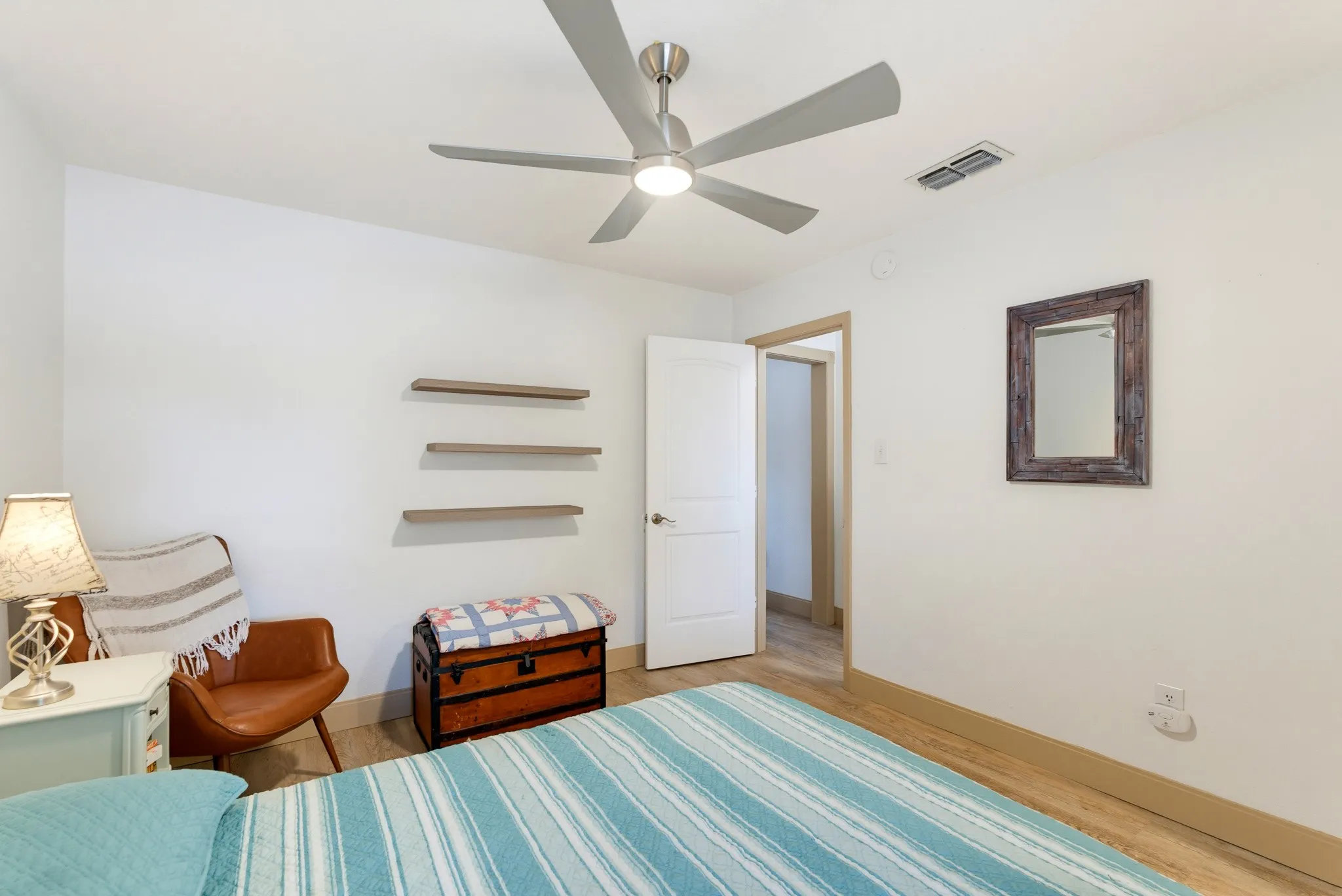 Ceiling fan with integrated lighting, wood-finish flooring, white walls, white trim, and a white interior door