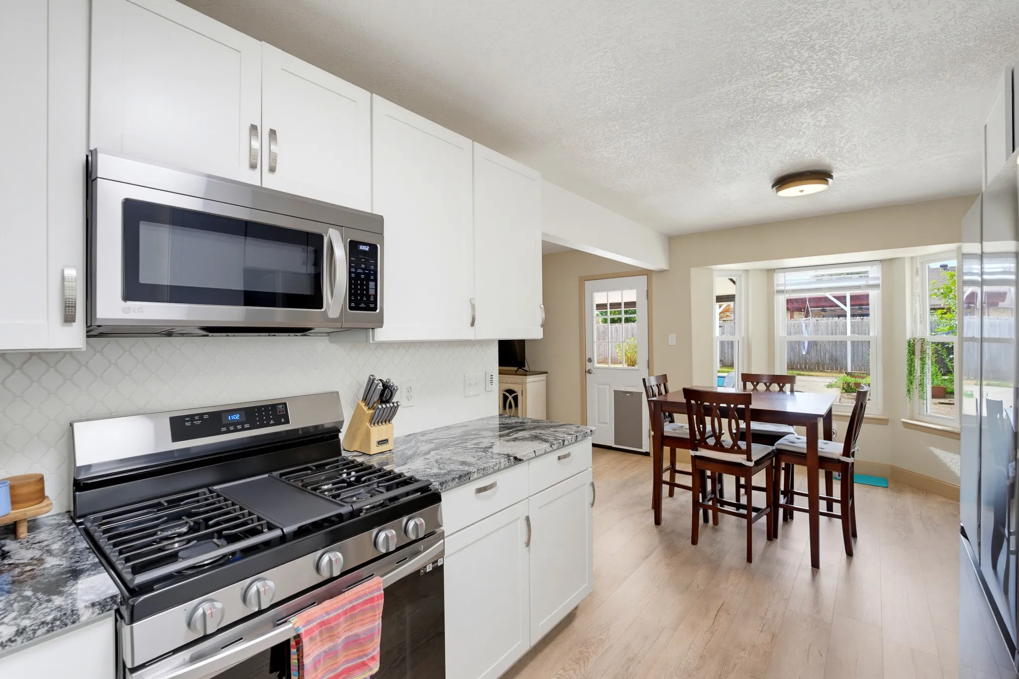 Kitchen featuring white shaker cabinetry, stainless steel appliances, and stone countertops