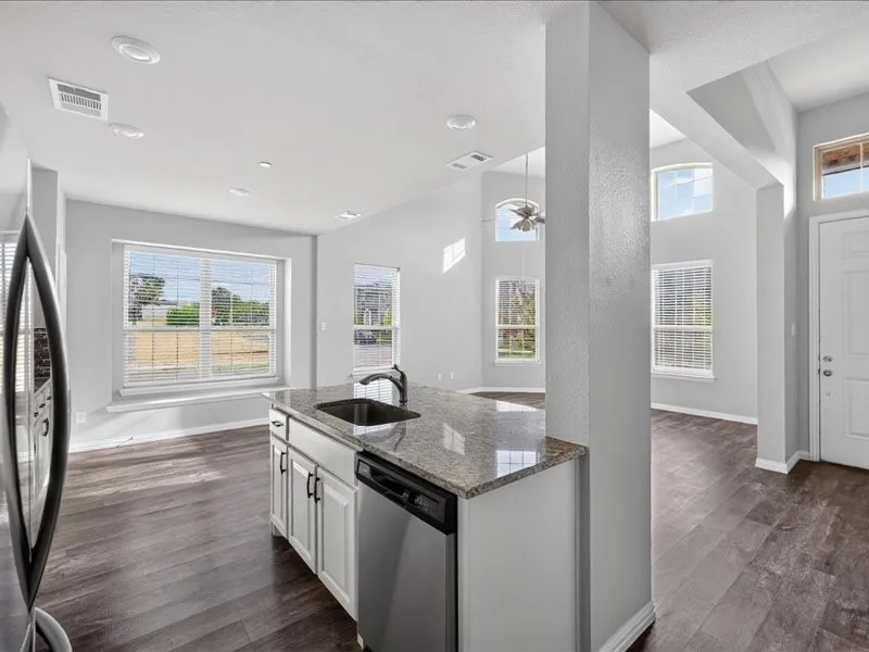 Kitchen island featuring a granite countertop, undermount sink, and stainless steel dishwasher