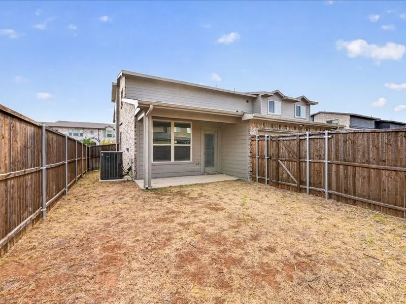Private backyard with wood fencing, a concrete patio, and a stone facade on the exterior