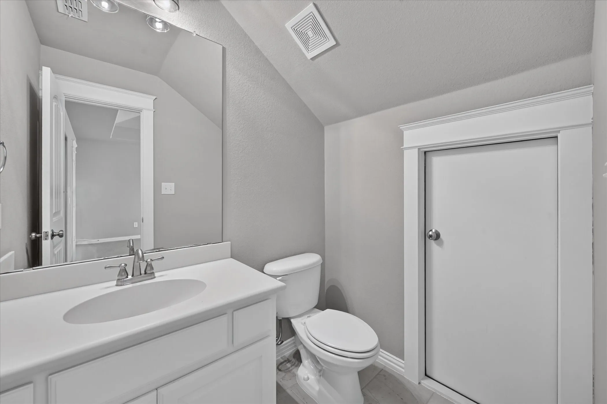 Vanity with an integrated sink, brushed nickel faucet, and overhead lighting