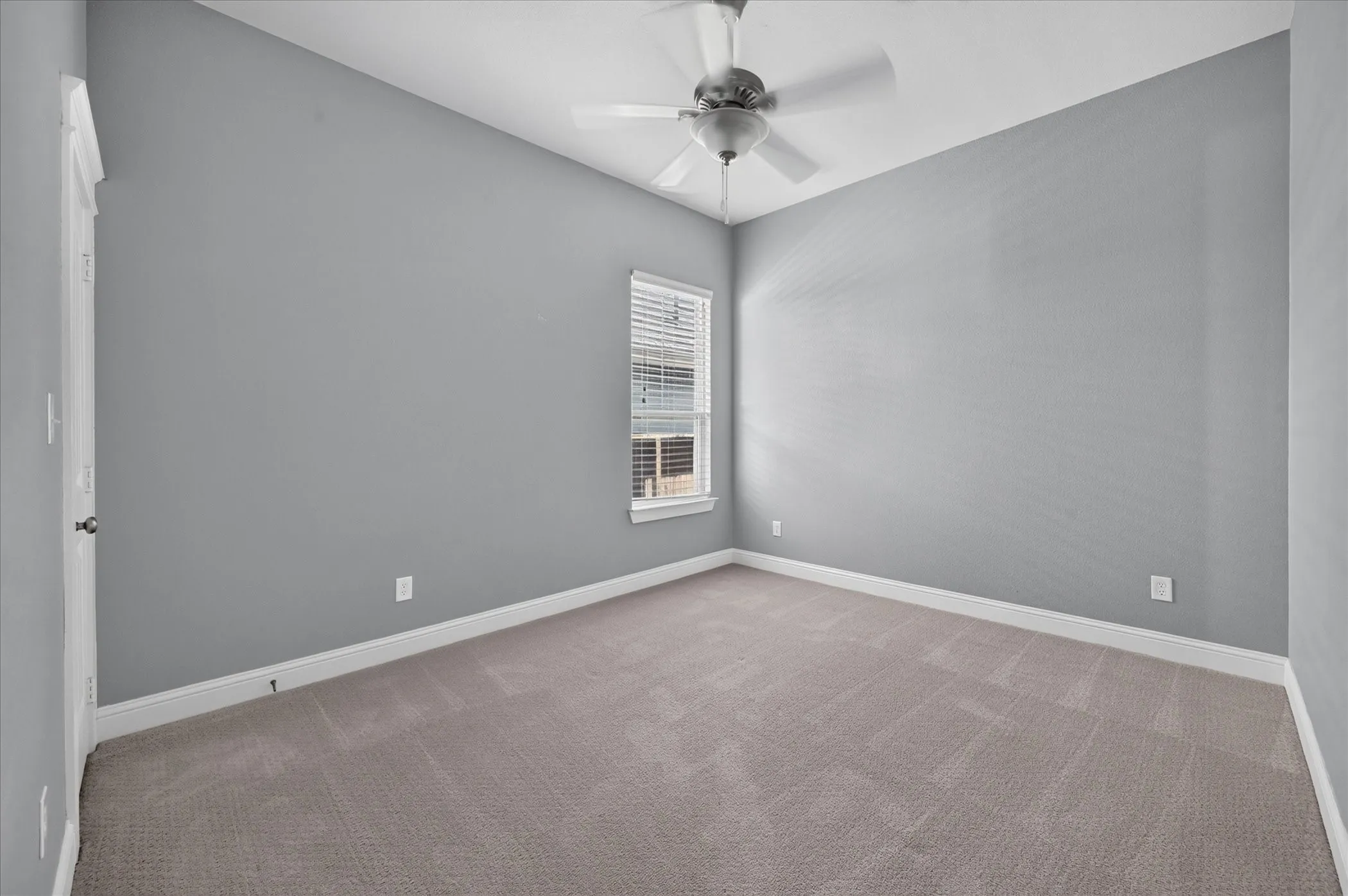 Carpeted room featuring a ceiling fan, window with blinds, and light gray walls