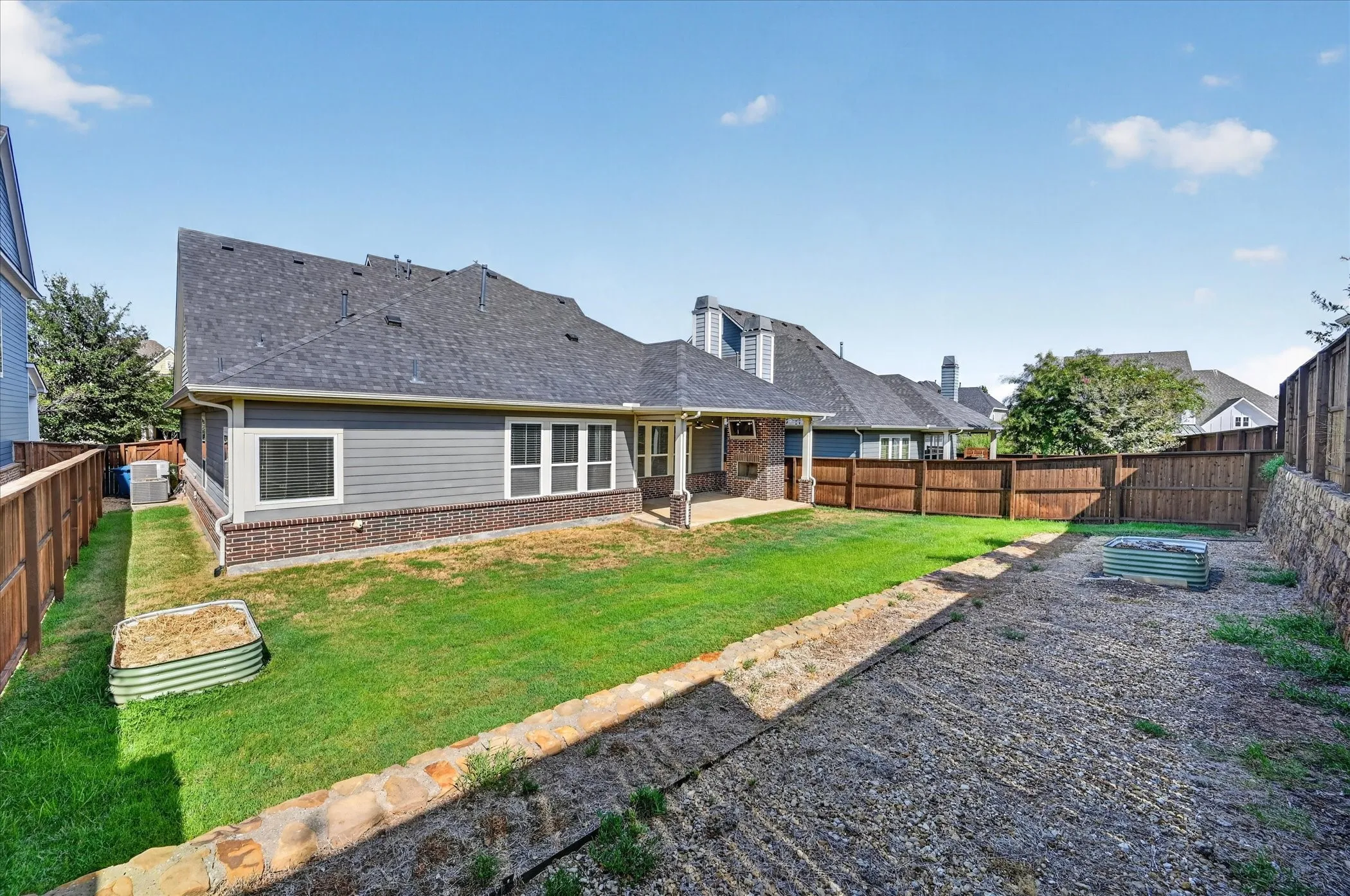 Expansive backyard with a covered patio, manicured lawn, and privacy fencing