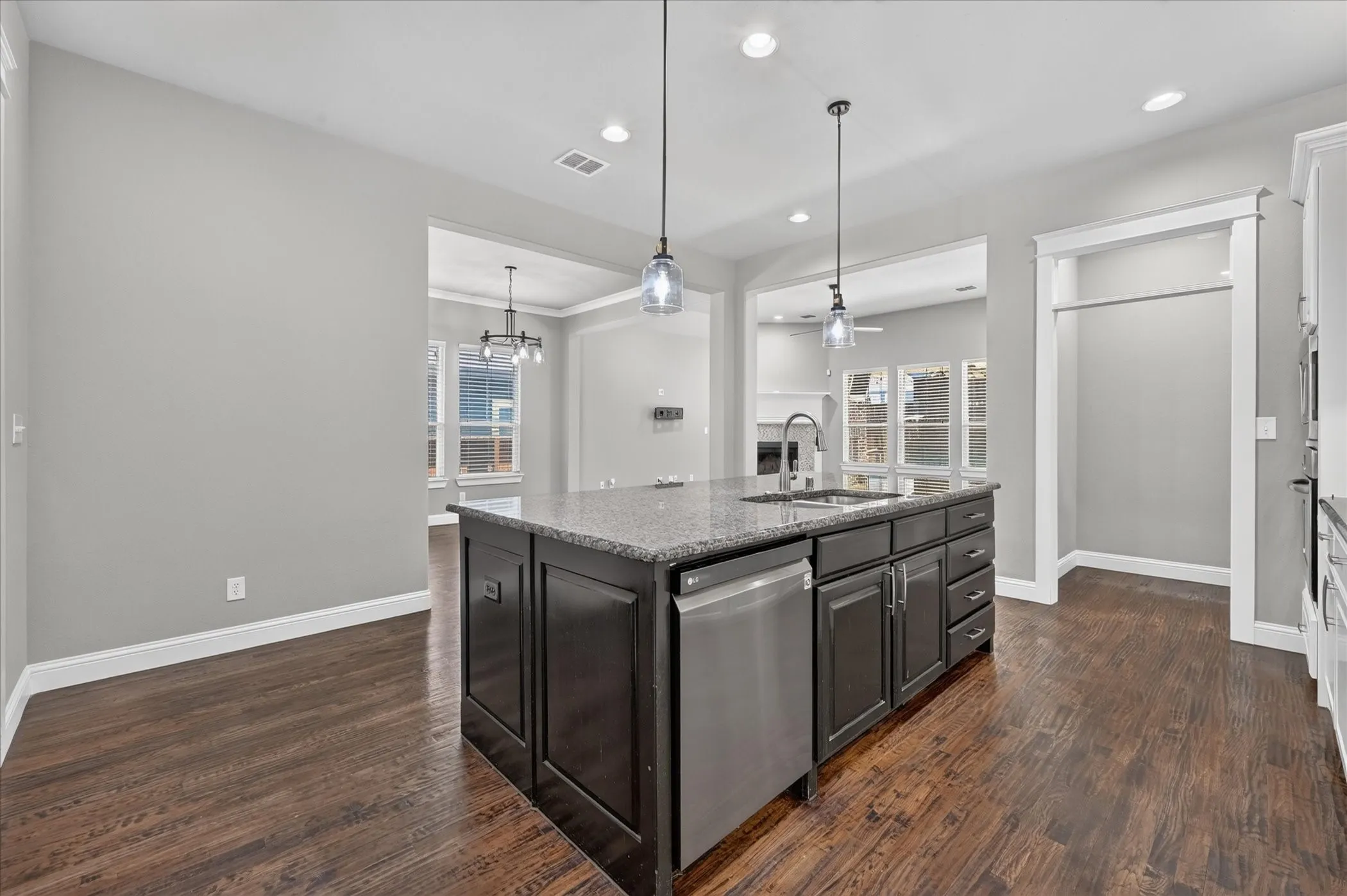 Kitchen island featuring dark cabinetry, an undermount sink, and a stainless steel dishwasher