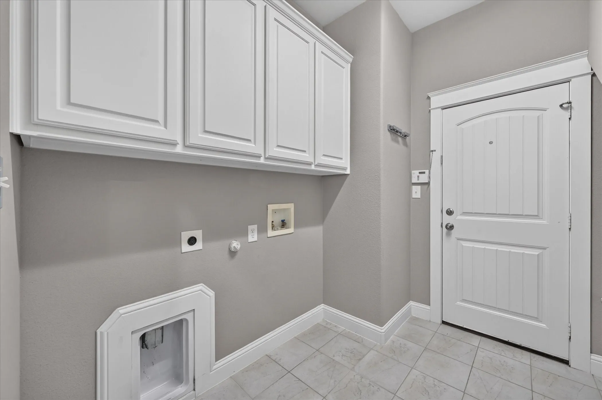 White shaker-style cabinetry, light gray wall paint, white trim, and light-toned tile flooring