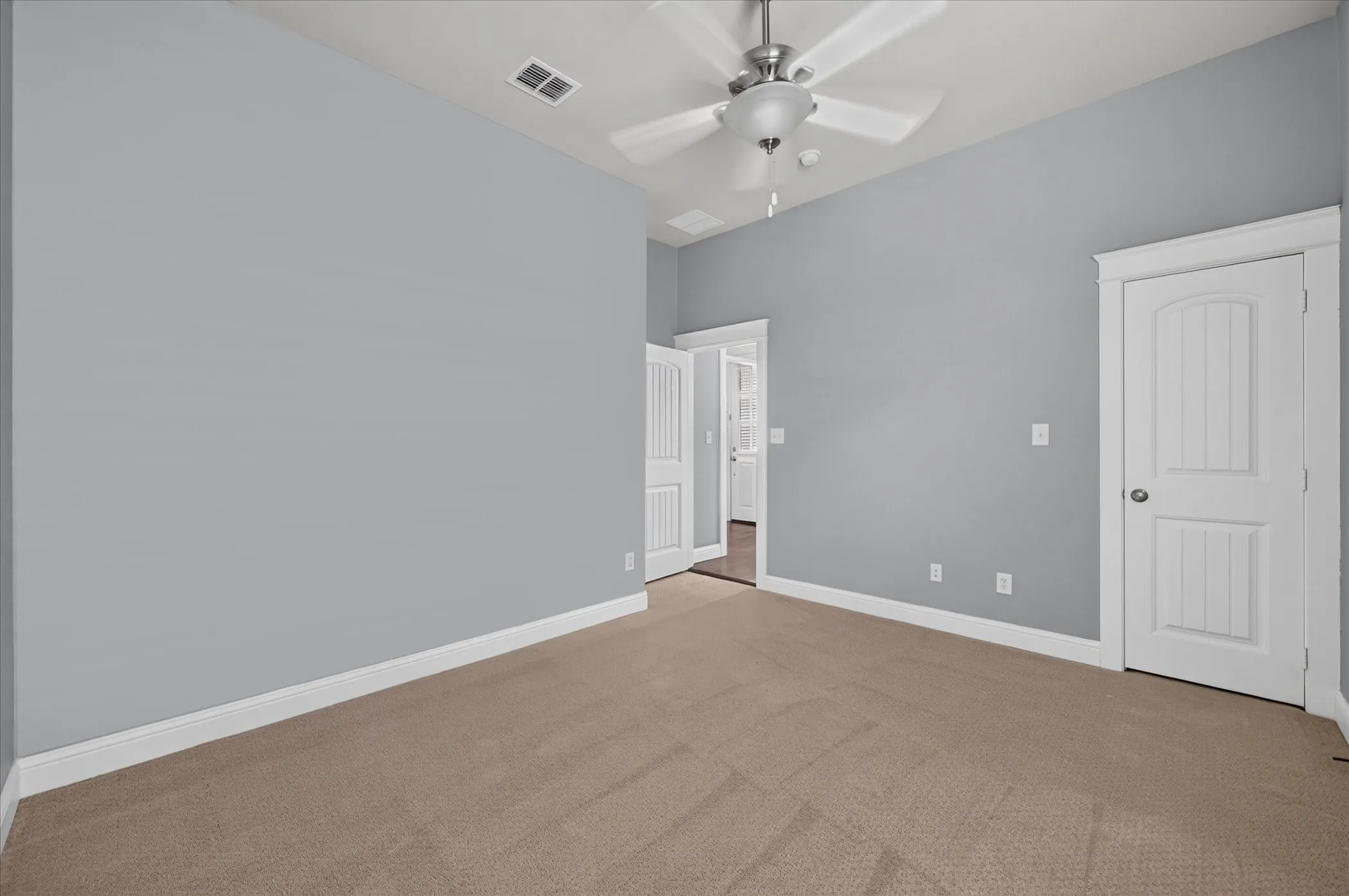 Neutral tone wall paint with white trim, brown carpet flooring, and a ceiling fan with integrated lighting