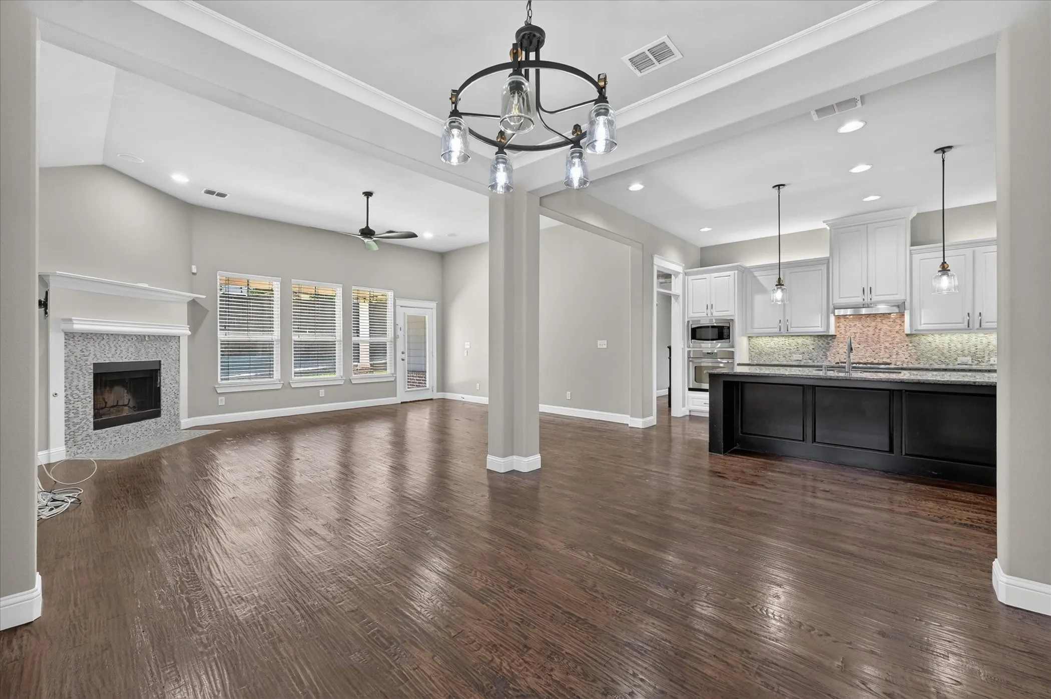 Expansive living space featuring wood-finish flooring, a fireplace with tile surround, and vaulted ceilings